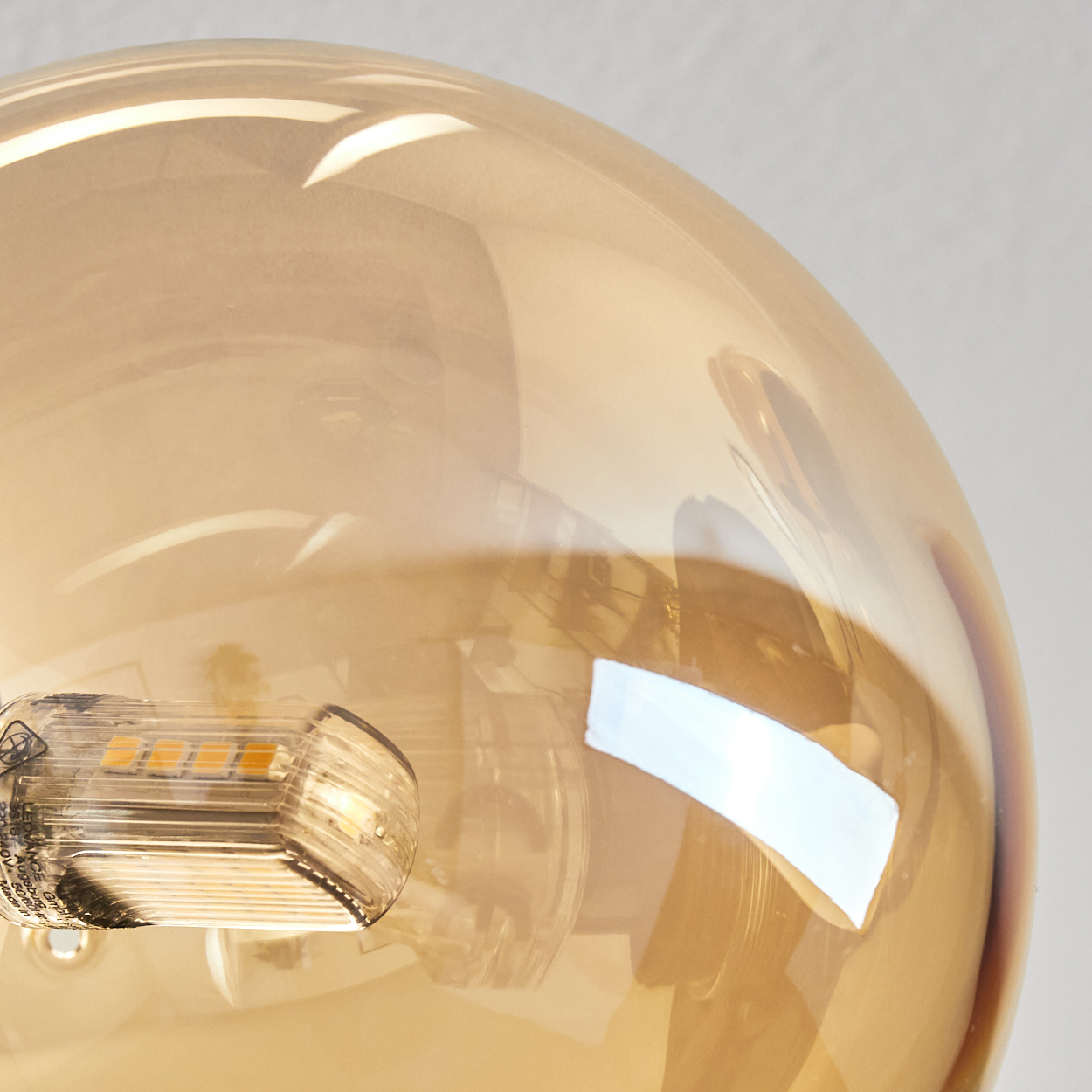 Nahaufnahme einer bernsteinfarbenen Glühbirne mit sichtbarer Lichtquelle.