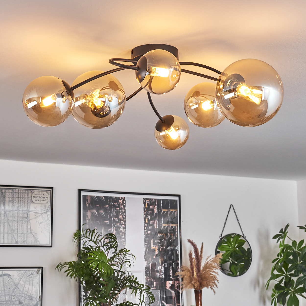 Eine Deckenlampe mit sechs Glaskugeln. Der Raum hat Pflanzen, Kunst und einen hängenden Spiegel.