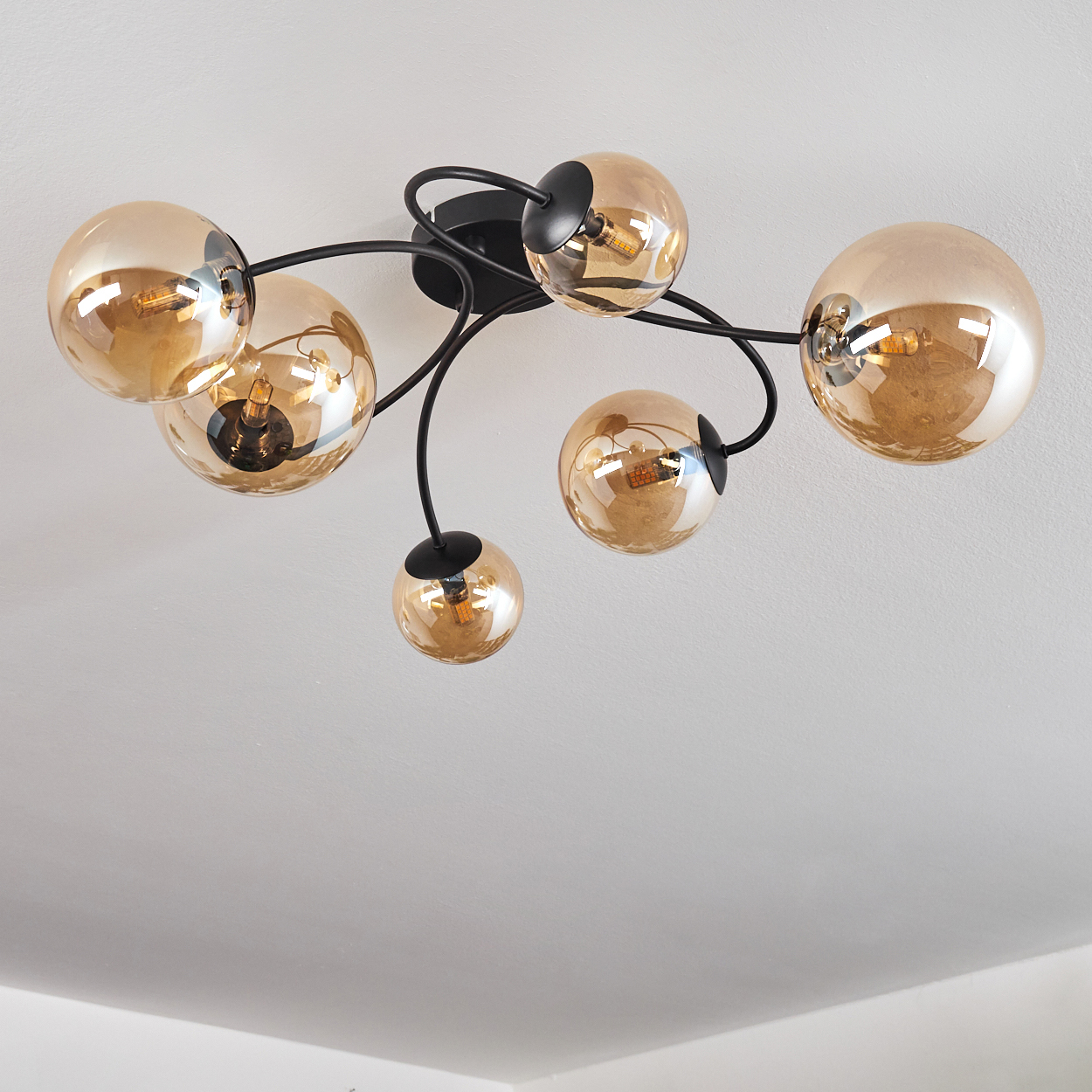 Eine Deckenlampe mit sechs Glaskugeln. Jede Kugel enthält eine Glühbirne.