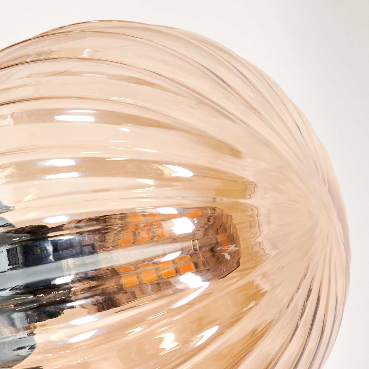 Nahaufnahme eines gerippten bernsteinfarbenen Glaskugel, die Licht reflektiert.