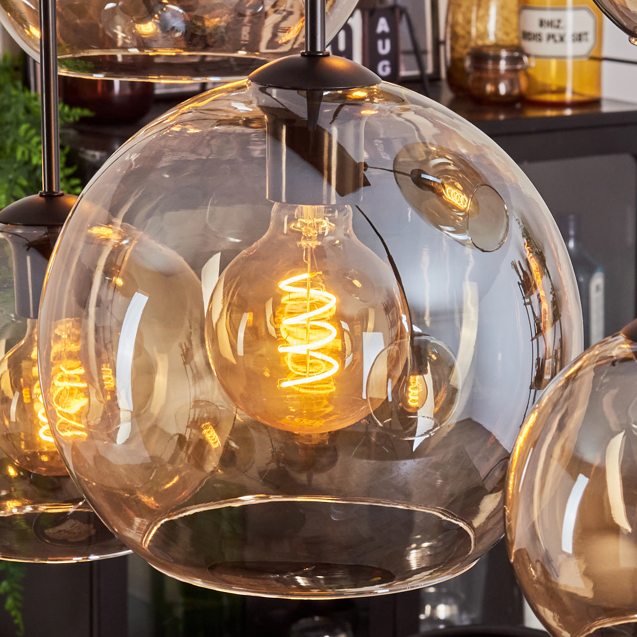 Nahaufnahme einer Leuchte mit bernsteinfarbenen Glaskugeln und sichtbaren Edison-Glühbirnen.