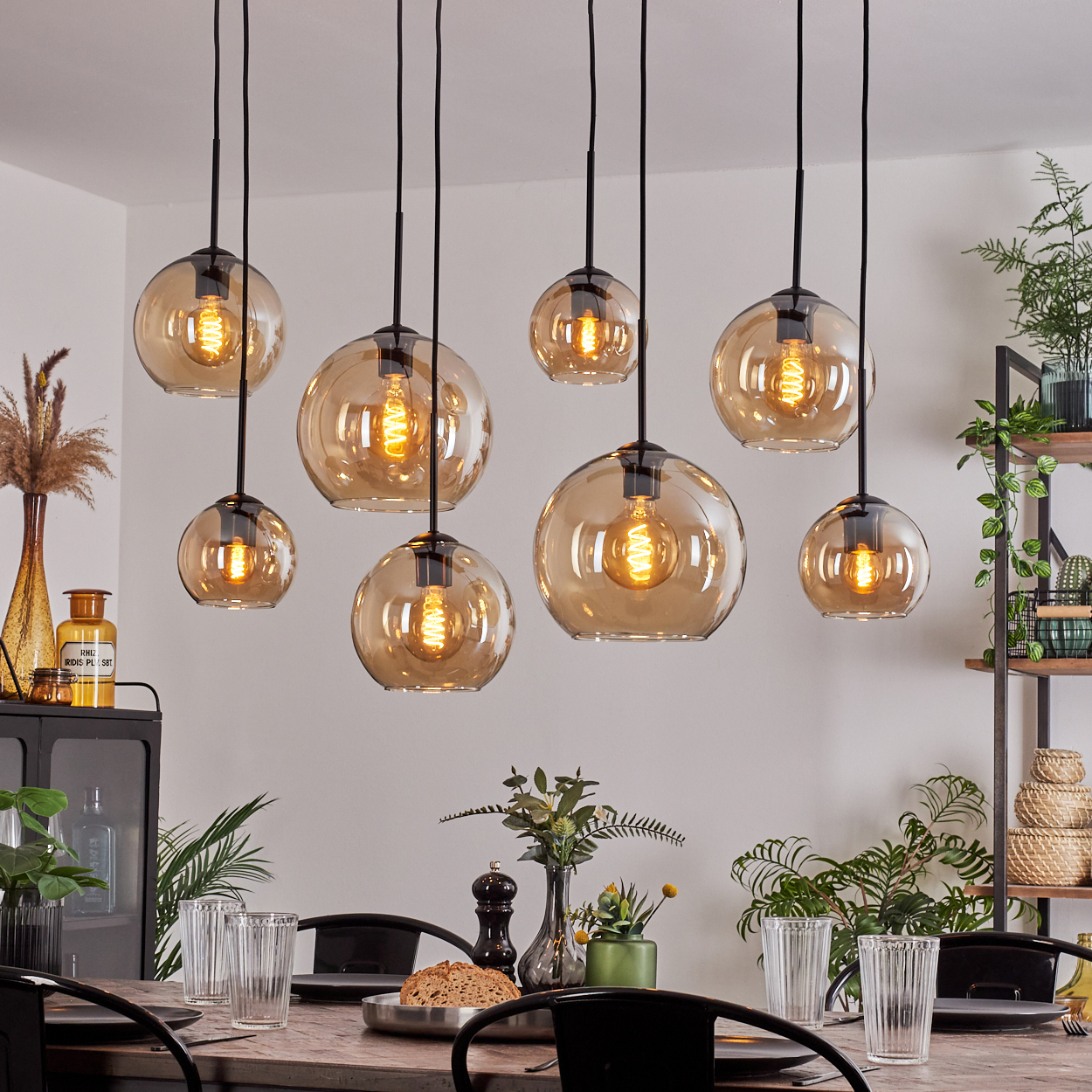 Esszimmer mit dunklem Holztisch und Hängeleuchten mit bernsteinfarbenen Glaskugeln.