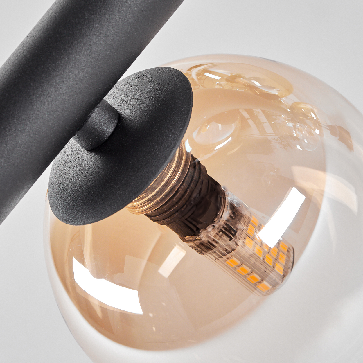 Nahaufnahme einer Glühbirne mit freiliegenden LED-Leuchten, in einem bernsteinfarbenen Glasschirm.