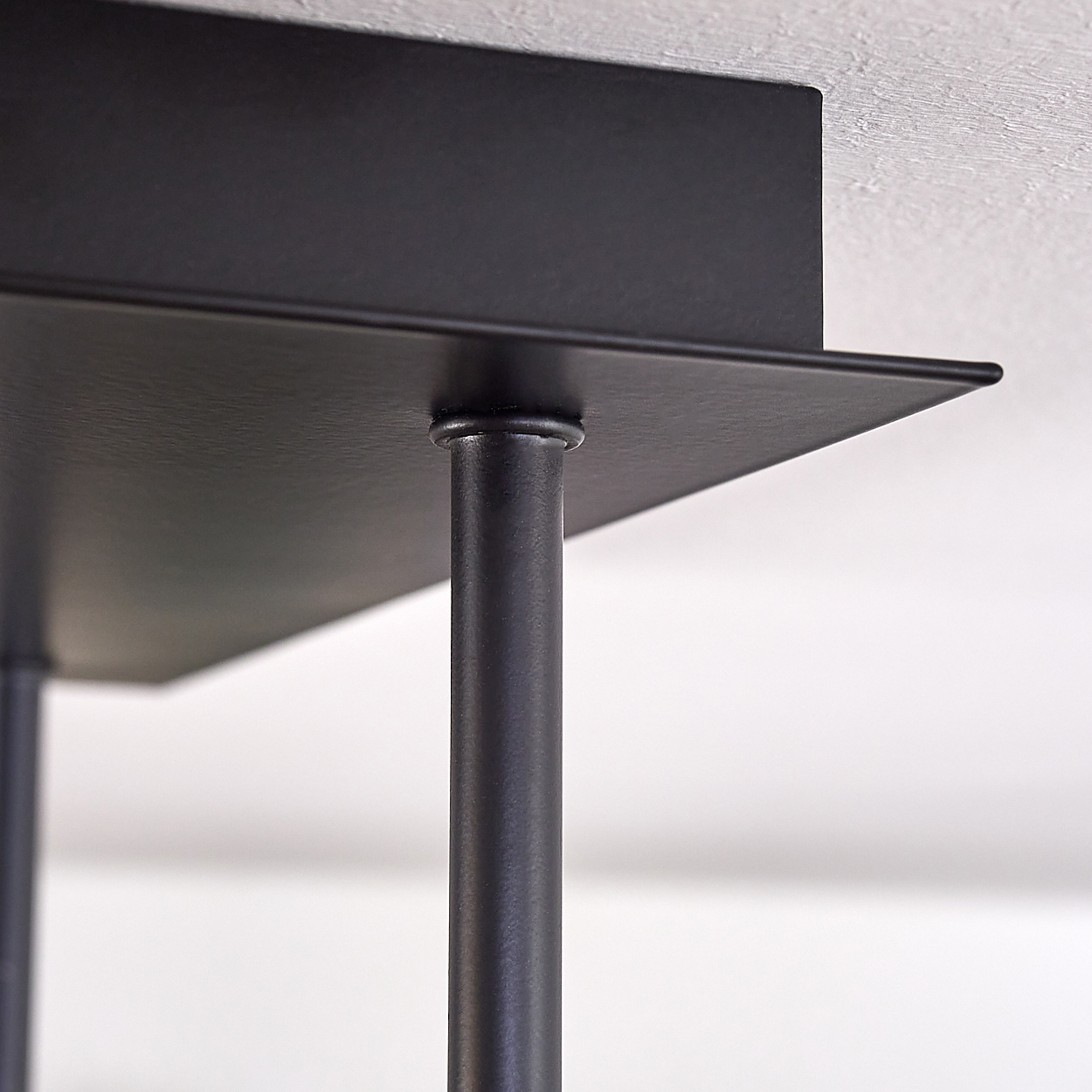Nahaufnahme der Befestigung einer schwarzen Deckenlampe an der Decke.