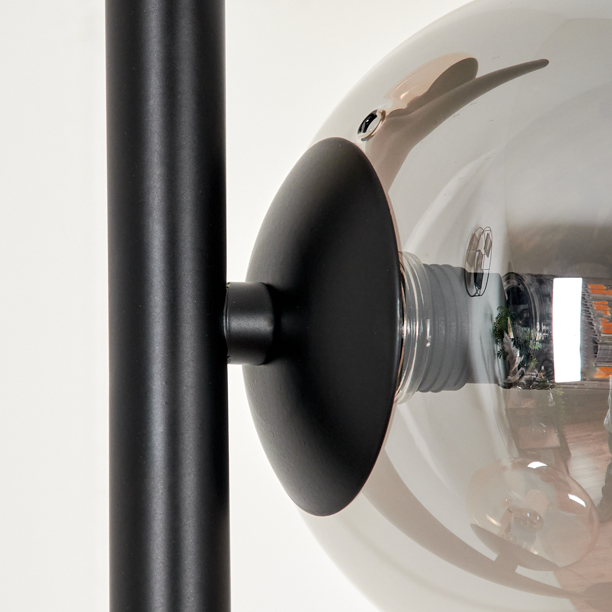 Nahaufnahme einer schwarzen Stehlampe mit einer grauen Glaskugel, die Lampendetails zeigt.