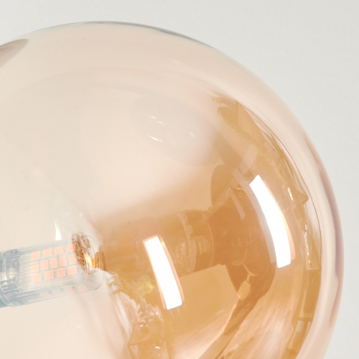Nahaufnahme einer Glühbirne in einer bernsteinfarbenen Glaskugel. LED-Leuchten sind sichtbar.