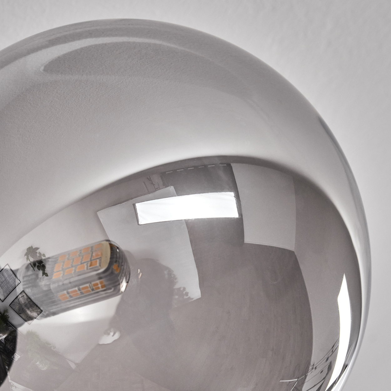 Nahaufnahme einer silberfarbenen Glaskugel mit einer Glühbirne. Weißer Hintergrund. LED-Leuchten sind sichtbar.