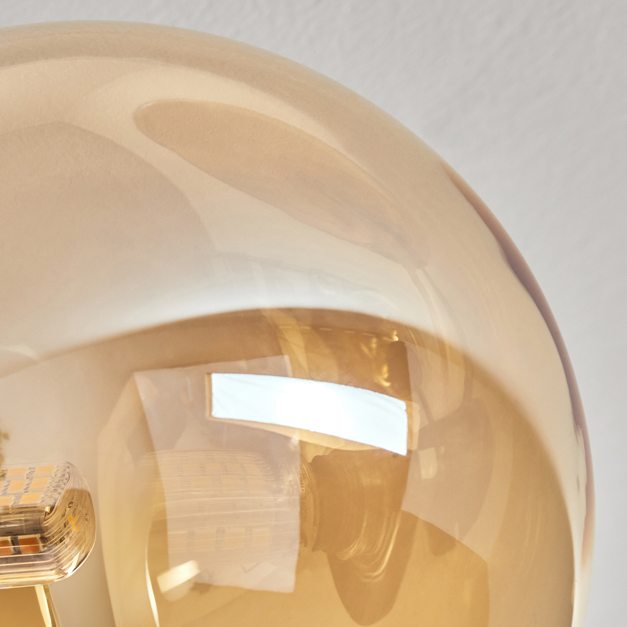 Nahaufnahme einer Glühbirne in einer bernsteinfarbenen Glaskugel. Das Licht ist hell.