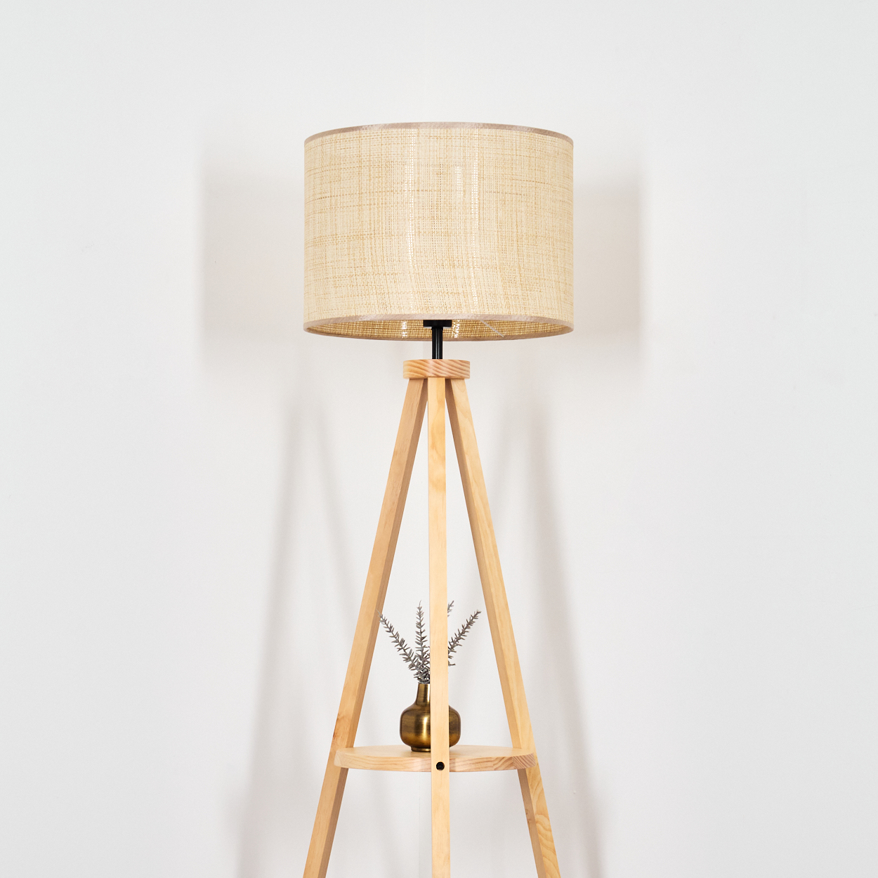 Holz-Stativlampe mit beigem Schirm, kleiner Vase mit Pflanzen, weißer Hintergrund.