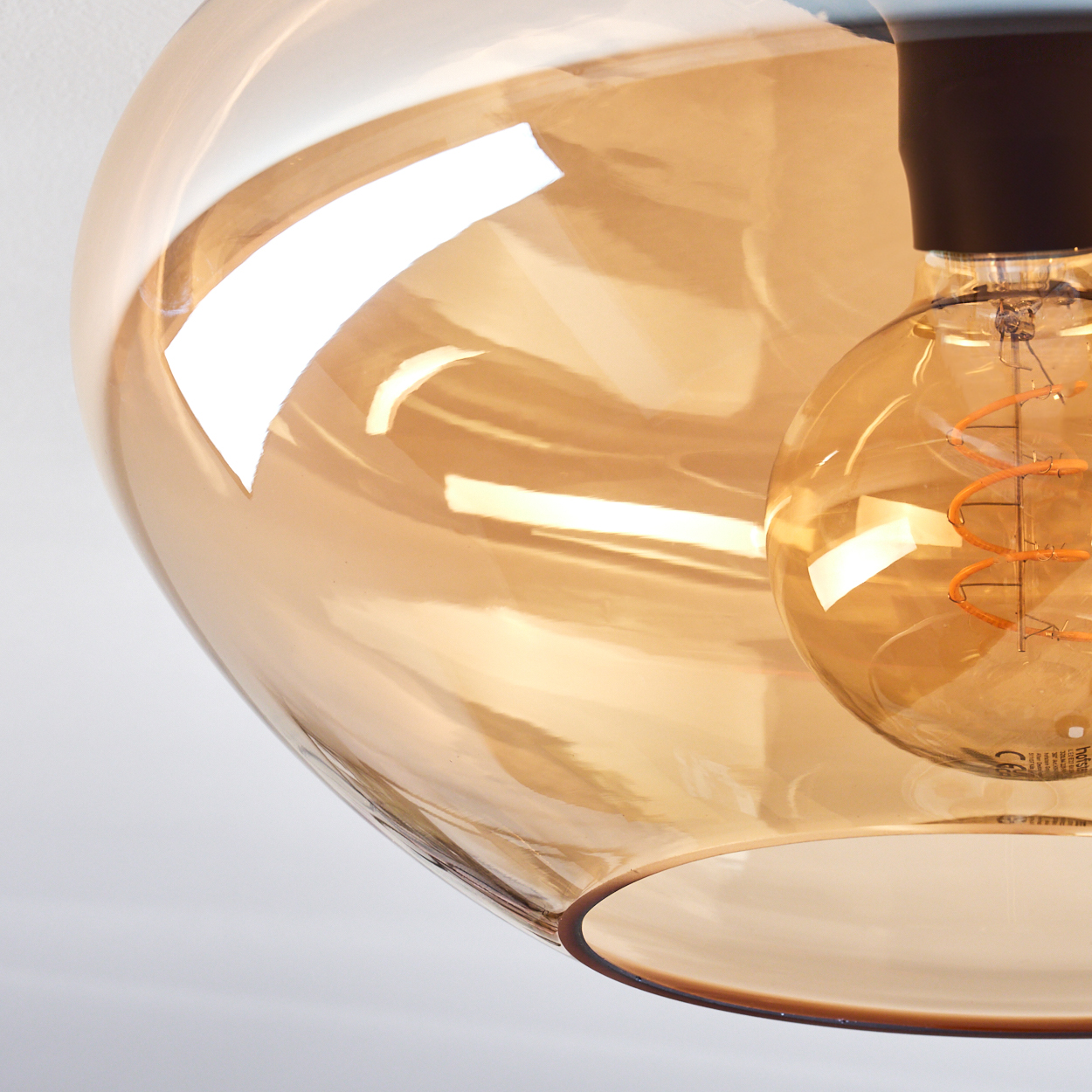 Nahaufnahme einer Deckenlampe mit goldenem Glasschirm und Glühbirne.