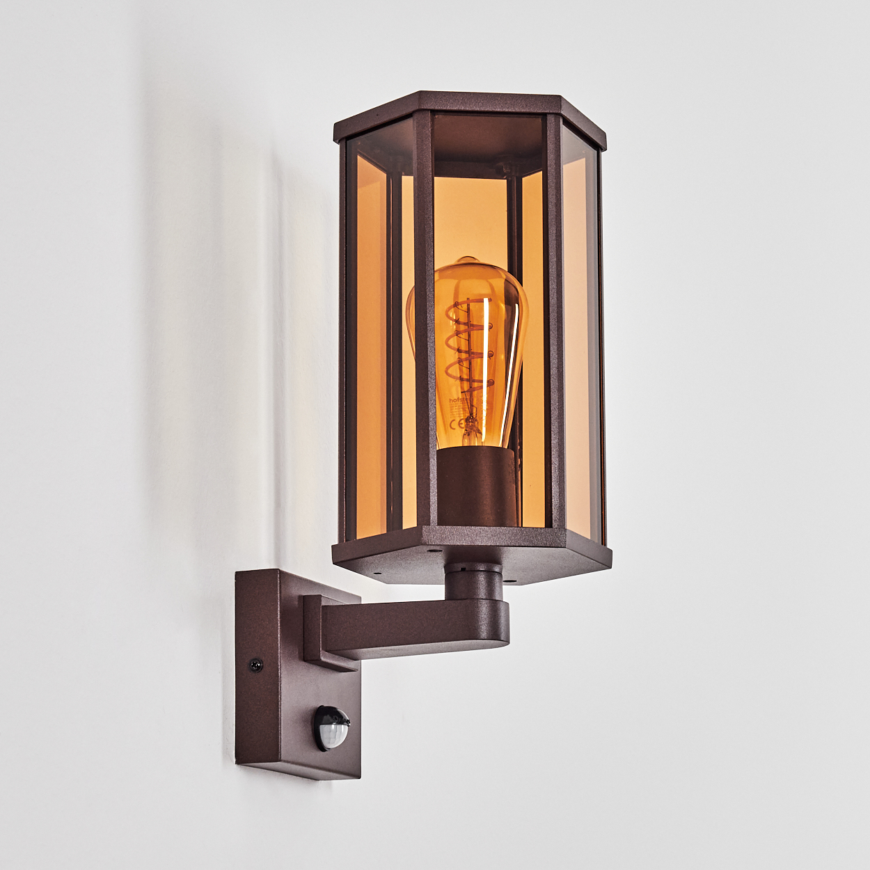Braune Wandleuchte mit Glasschirm und Edison-Glühbirne. Sie hat einen Bewegungssensor an der Wand.