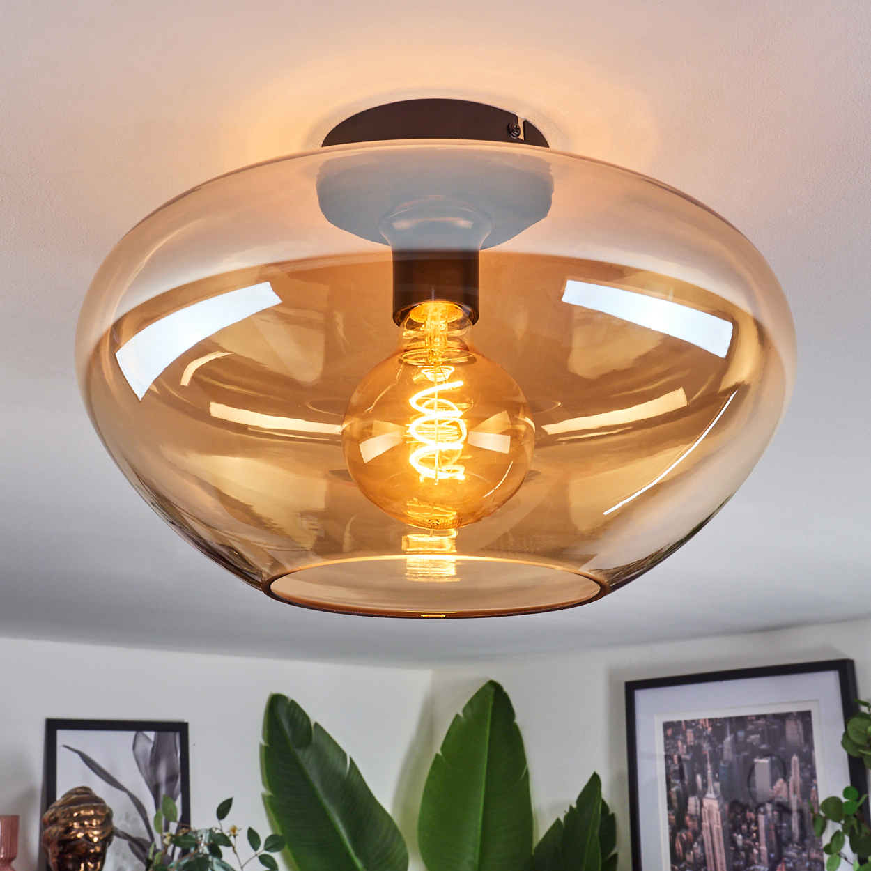 Deckenlampe mit goldenem Glasschirm und sichtbarer Glühbirne.