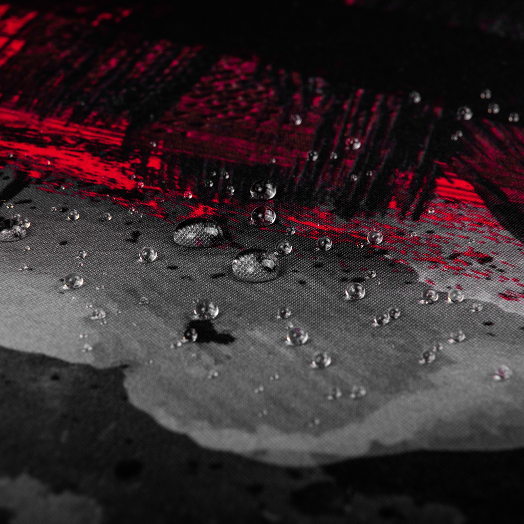 Krople wody na czerwono-czarnej wzorzystej powierzchni. Zbliżenie.