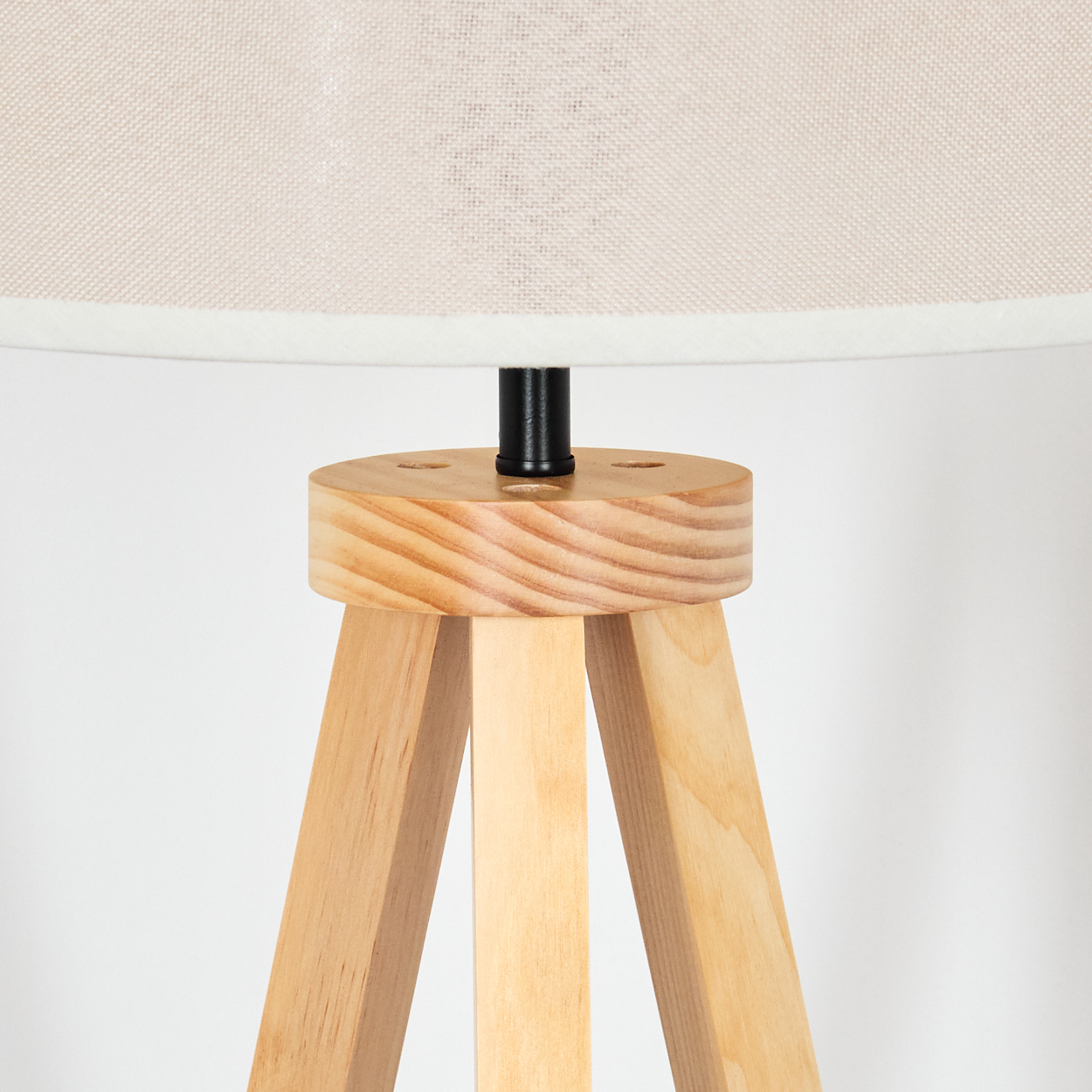 Nahaufnahme eines Holz-Stativfußes, der eine Lampe trägt. Die Lampe hat einen weißen Schirm.