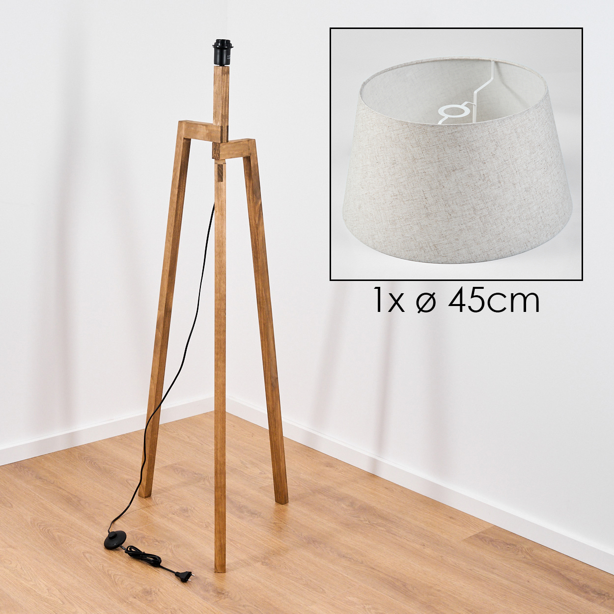 Holz-Stativlampe mit beigem Lampenschirm, mit eingesetztem Bild vor weißer Wand.