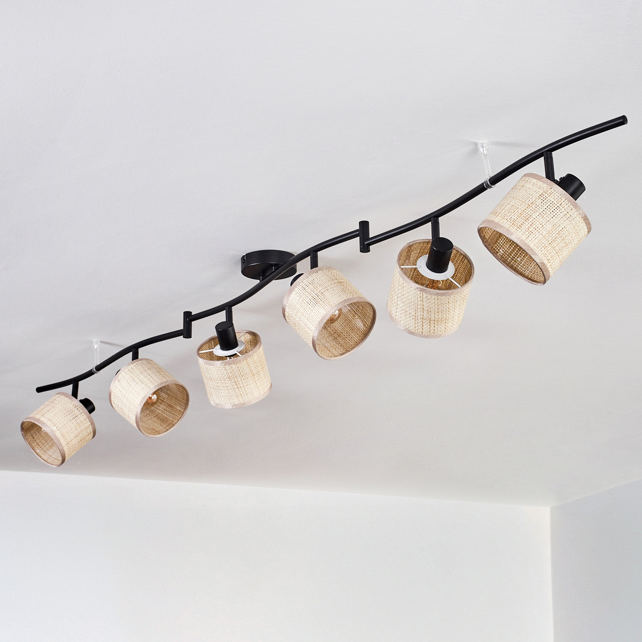 Deckenstrahler mit sechs Rattanschirmen. Weiße Decke und Hintergrund.
