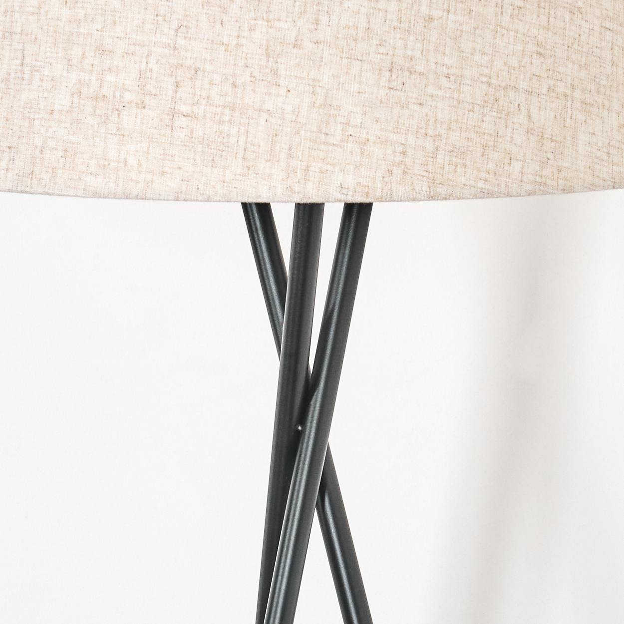 Nahaufnahme einer schwarzen Metalllampe mit beigem Lampenschirm. Weißer Hintergrund.