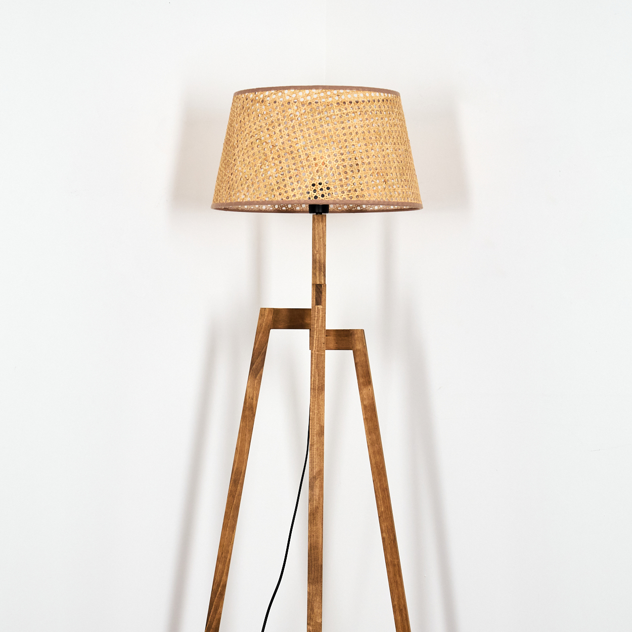 Holz-Stativ-Stehlampe mit gewebtem Schirm. Weißer Hintergrund.