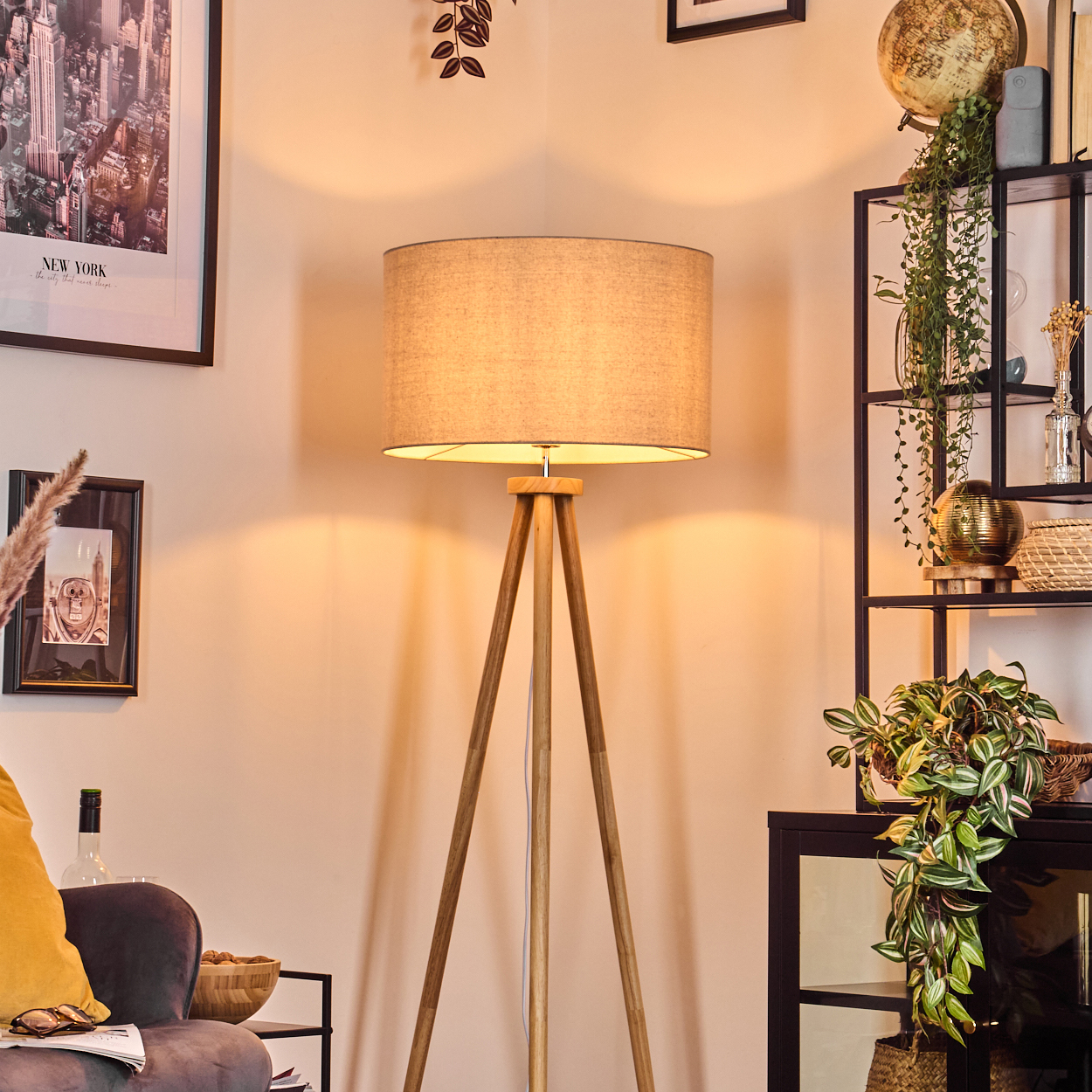 Eine Stehlampe mit beigem Schirm in einem Wohnzimmer, mit Dekoration und Pflanzen.