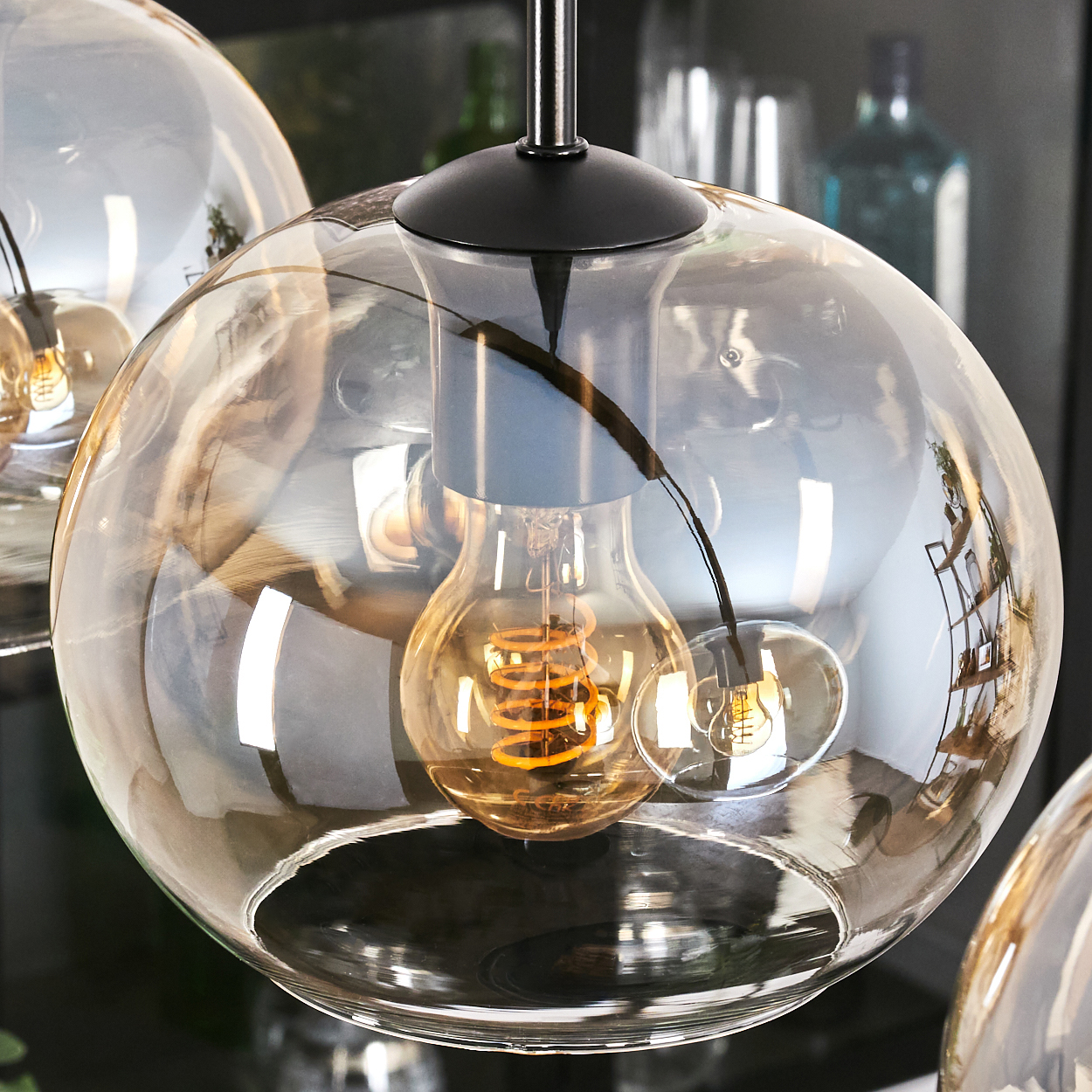 Nahaufnahme einer Pendelleuchte mit kugelförmigem Glas und einer Wendelglühbirne.