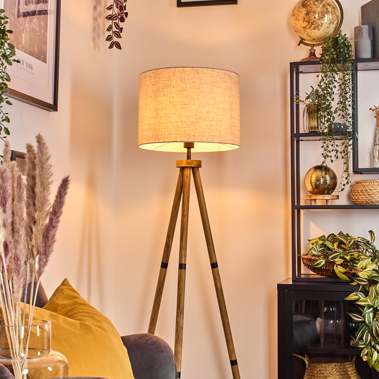 Stativ-Stehlampe mit beigem Schirm in Wohnzimmer mit Pflanzen und Deko.