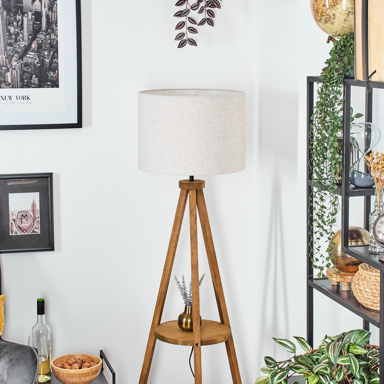 Wohnzimmer mit Holz-Dreibein-Lampe, Regalen und Dekoration.
