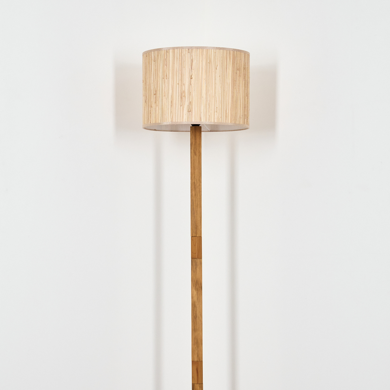 Holz-Stehlampe mit beigem Lampenschirm.
