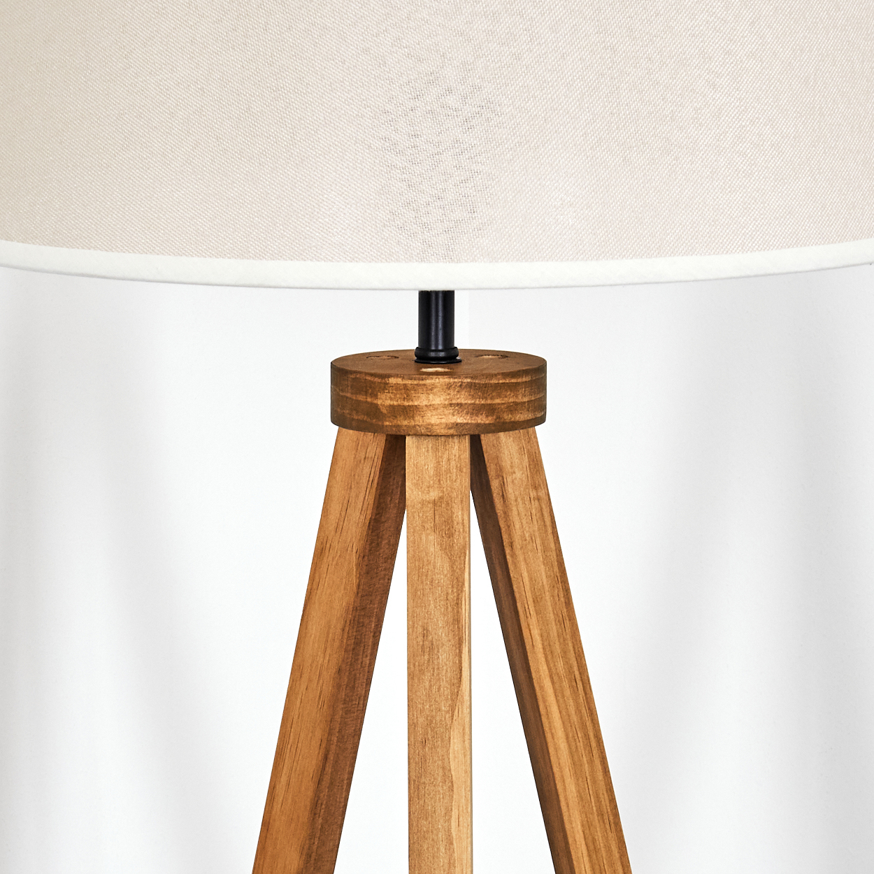 Nahaufnahme des Holz-Dreibein-Lampenfußes. Die Beine verbinden sich mit einem Ring.