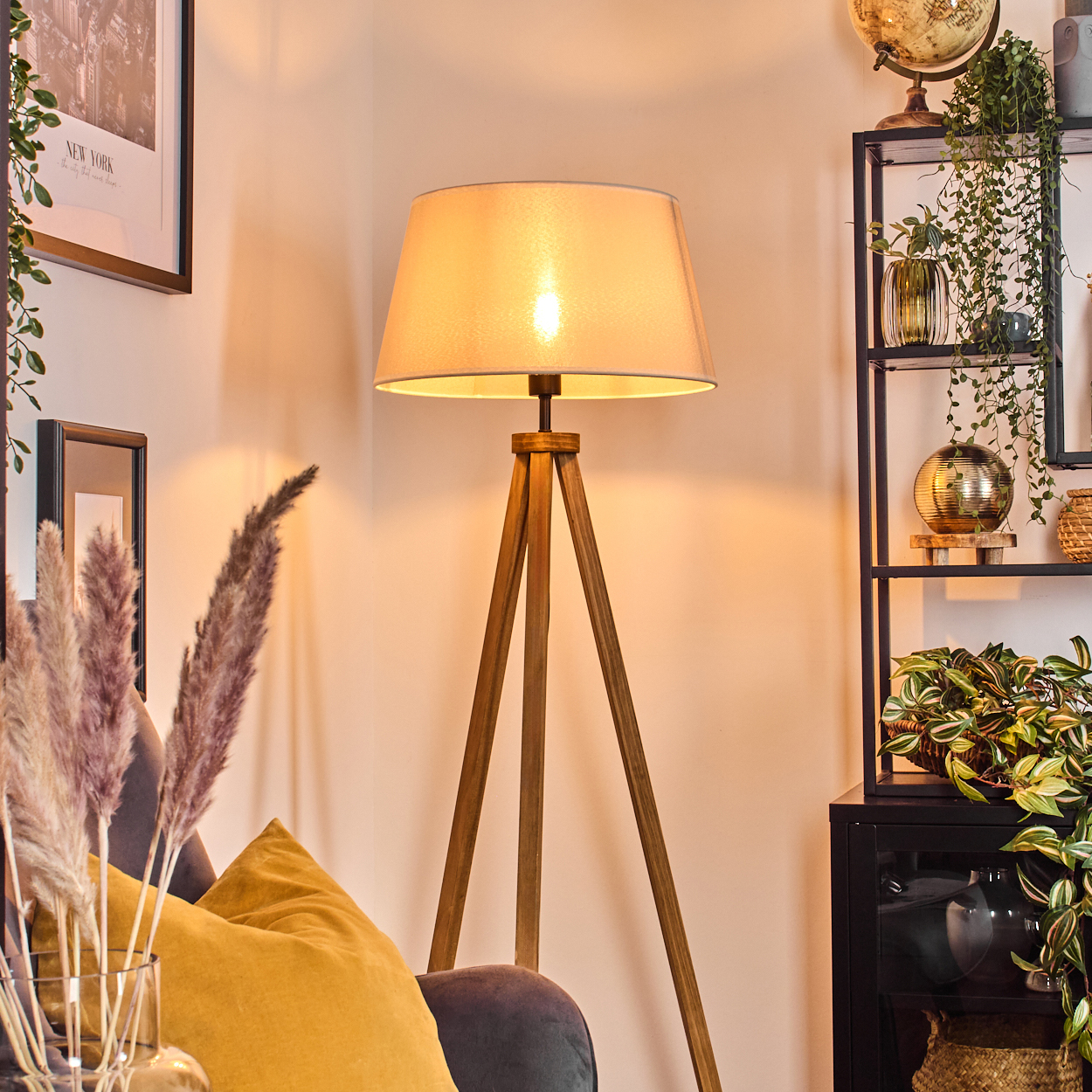 Beleuchtete Stativlampe im Wohnzimmer mit Pflanzen und Dekoration.