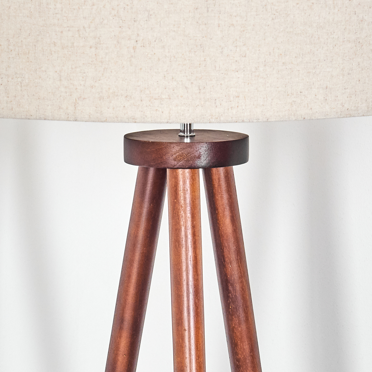Nahaufnahme des Sockels einer Holz-Stehlampe mit beigem Schirm.