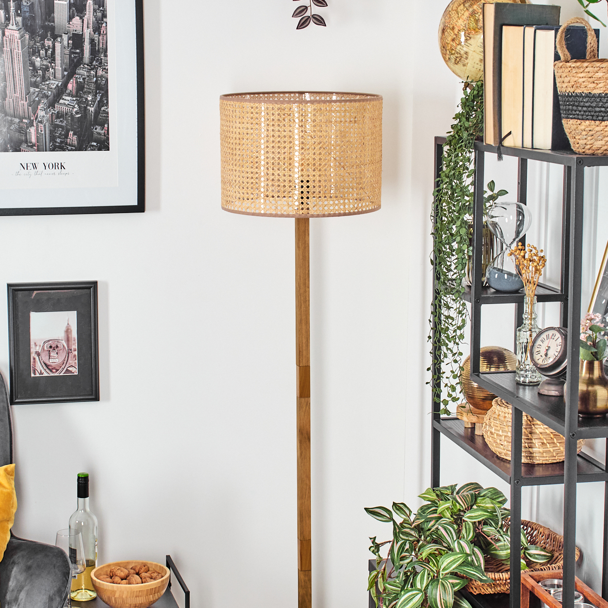 Ein Raum mit Stehlampe und gewebtem Lampenschirm. Regal mit Gegenständen sichtbar.