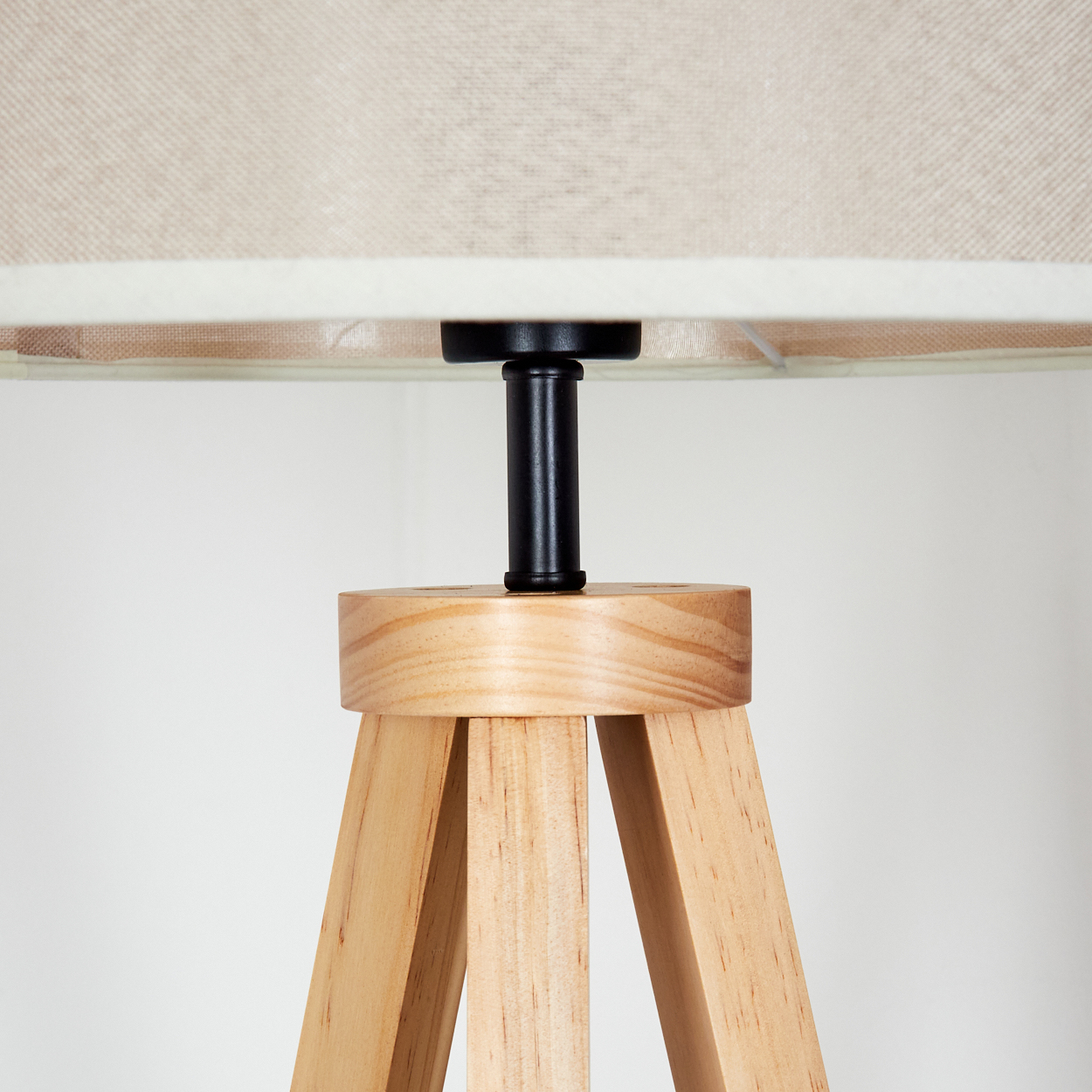 Holzstativ-Lampensockel mit beigem Lampenschirm. Schwarze zentrale Stütze.