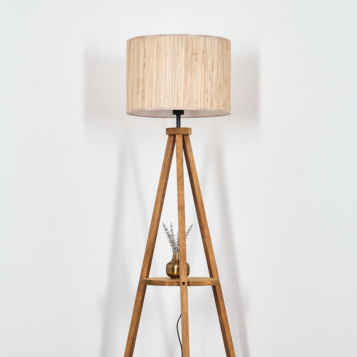Stehlampe aus Holz mit gewebtem Schirm, kleine Vase auf einem Regal.