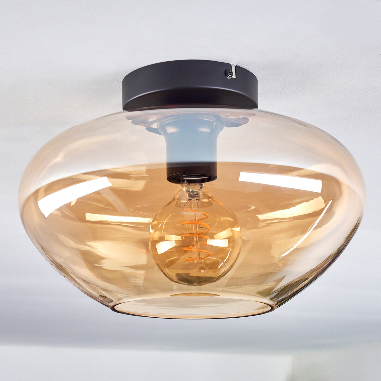 Draufsicht auf eine hängende Amber-Glaslampe mit Spiralglühbirne.