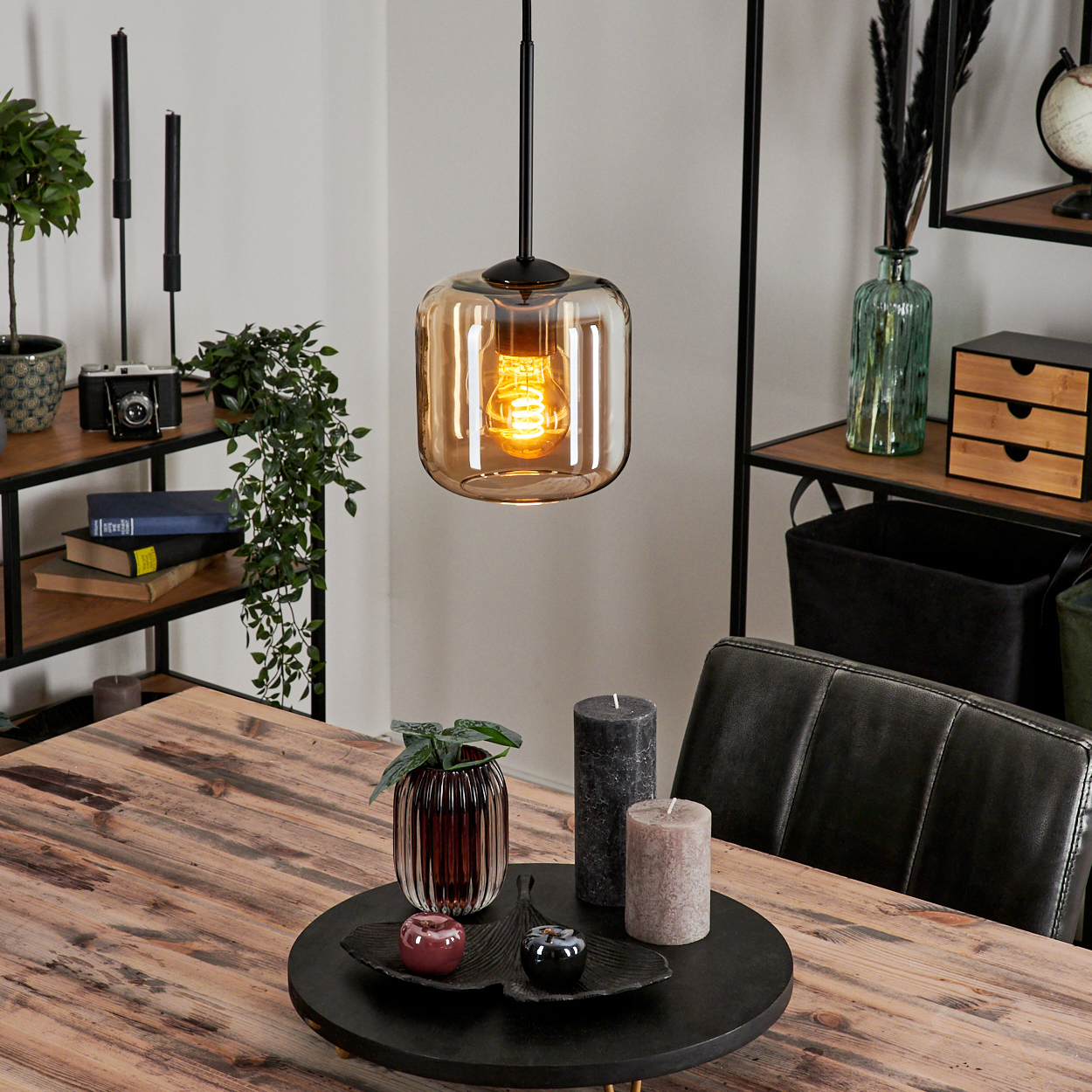 Esszimmer mit Amber-Glas-Hängeleuchte und Dekoration auf einem Holztisch.