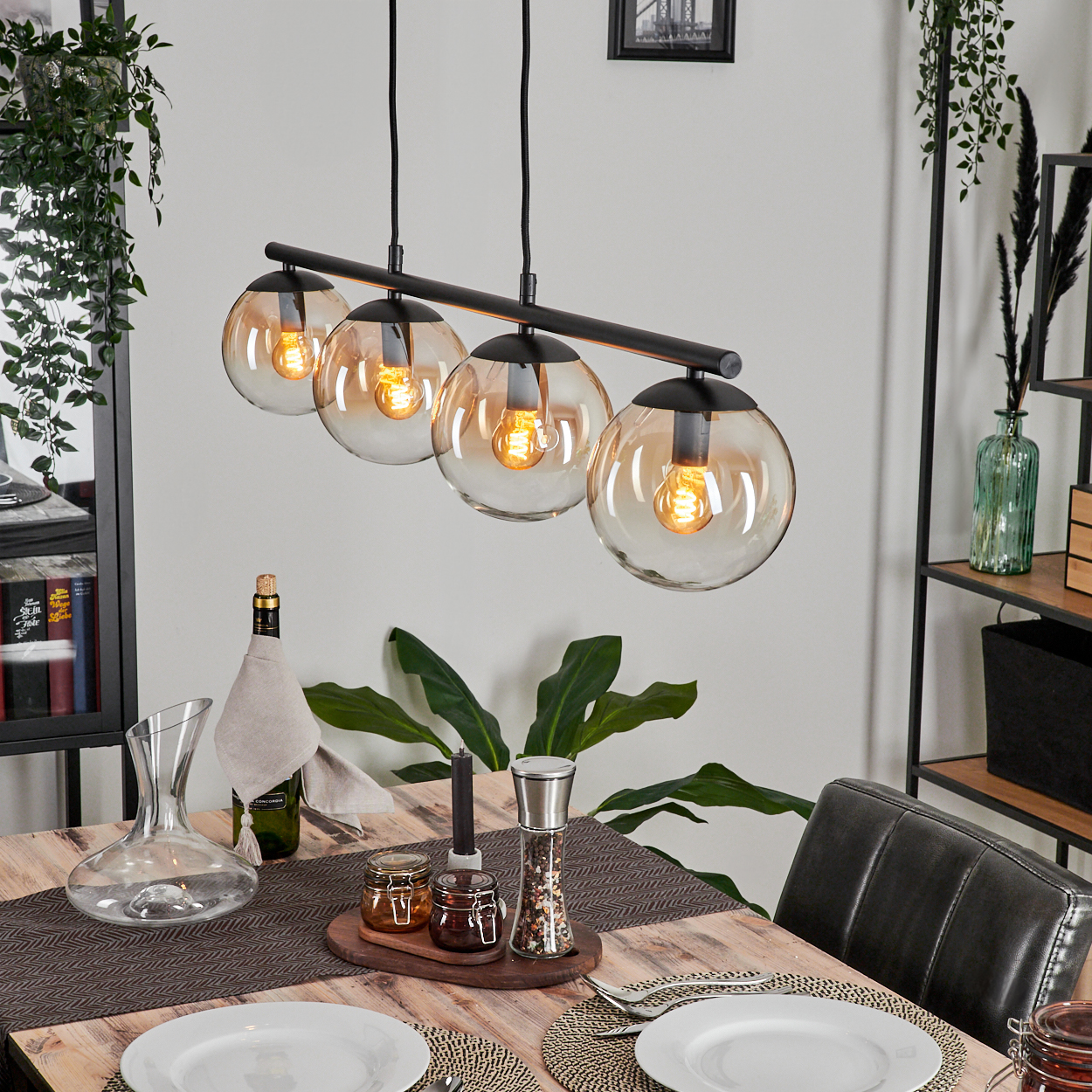 Esszimmer mit vier Amber-Glaskugellampen und Dekoration. Holztisch sichtbar.