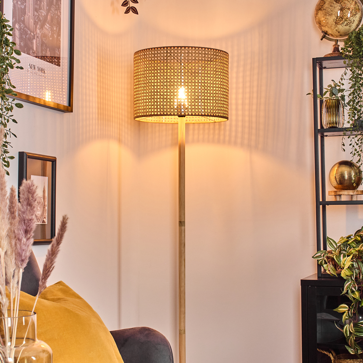 Eine Stehlampe mit gewebtem Schirm und Holzständer, beleuchtet in einem Wohnzimmer.