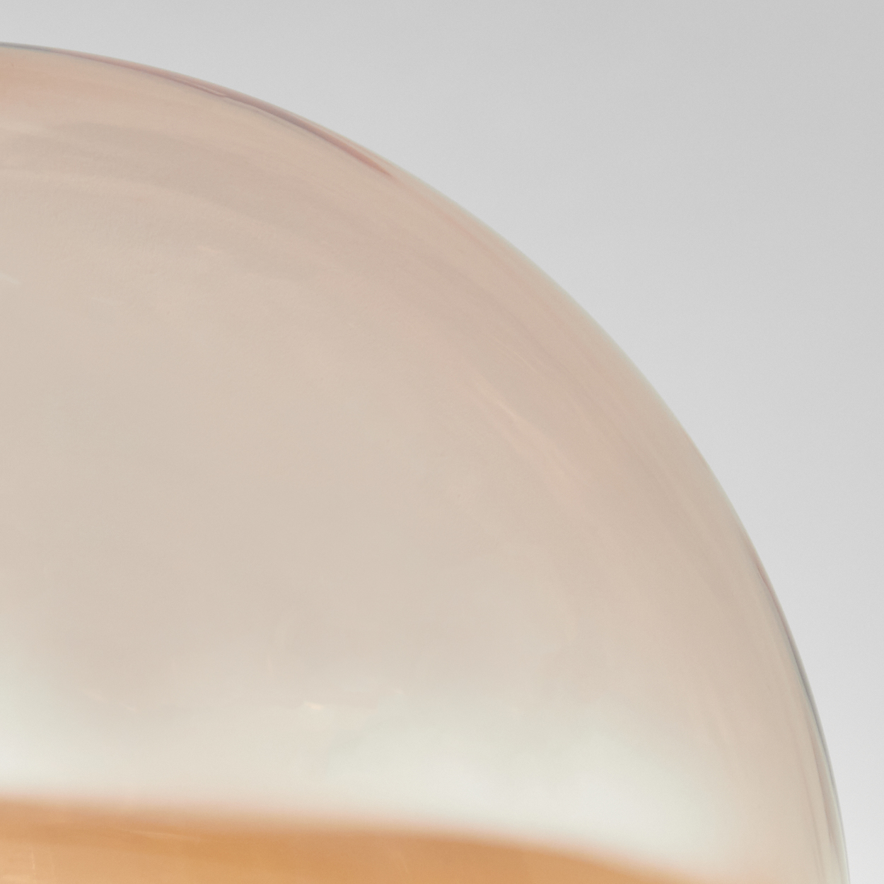 Nahaufnahme einer Glaskugel einer Lampe. Sie ist transparent und hat eine bernsteinfarbene Farbe.