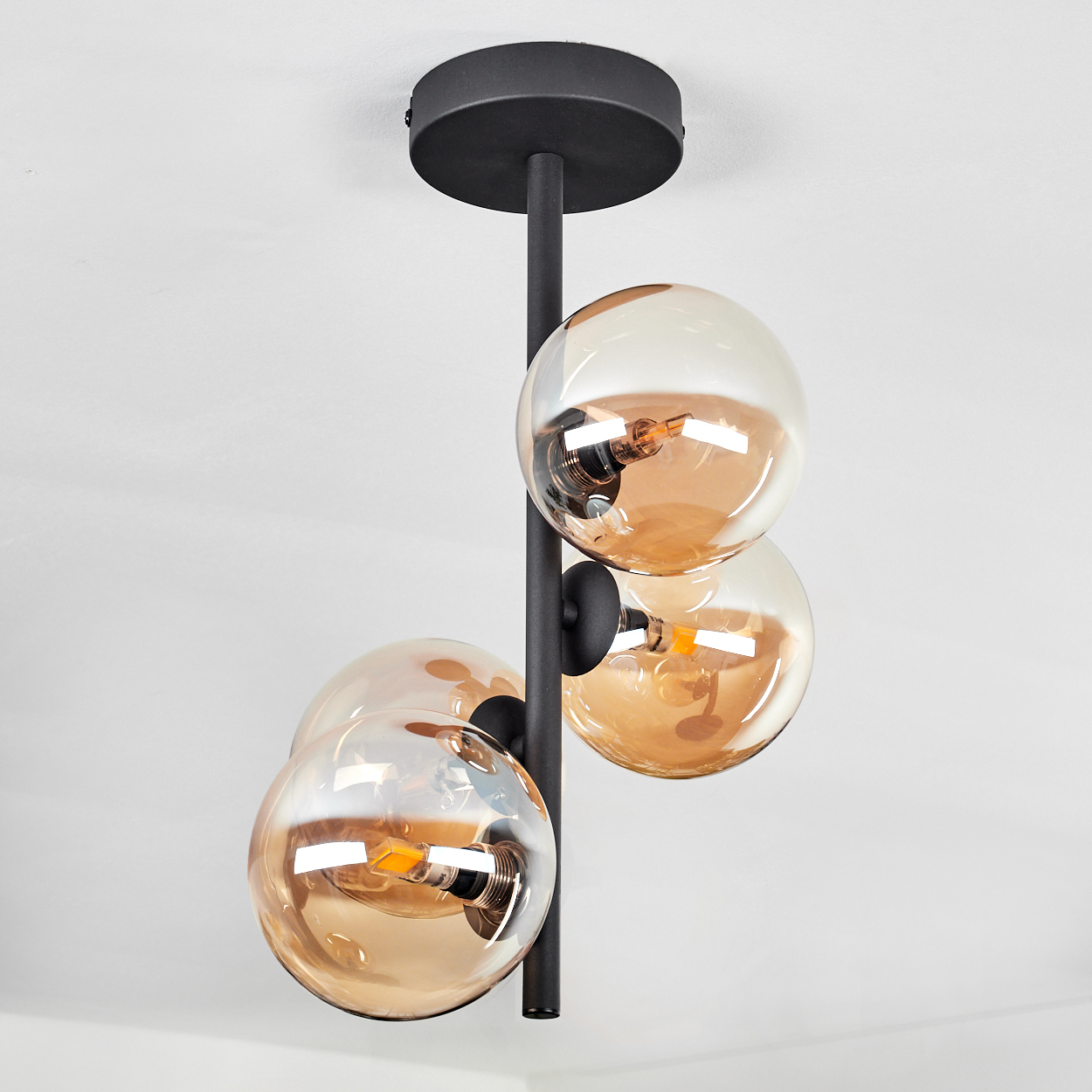 Deckenlampe mit vier transparenten Kugel-Schirmen, schwarze Armaturen.
