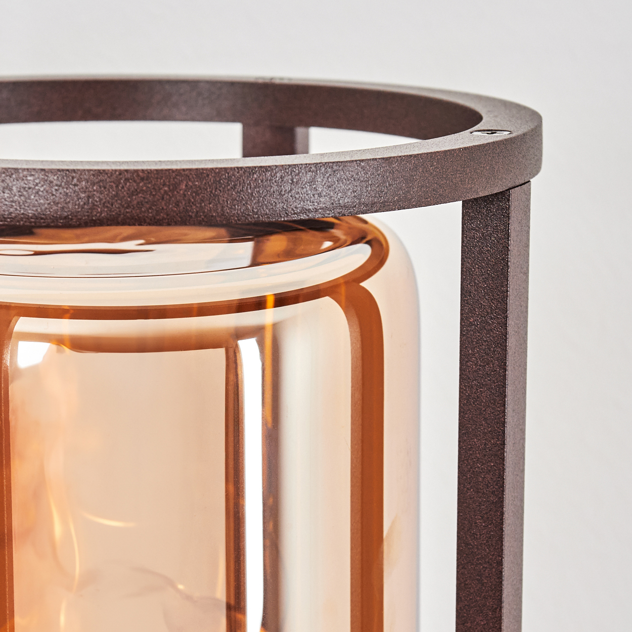 Nahaufnahme eines Lampenschirms mit braunem Metallrahmen und bernsteinfarbenem Glas.