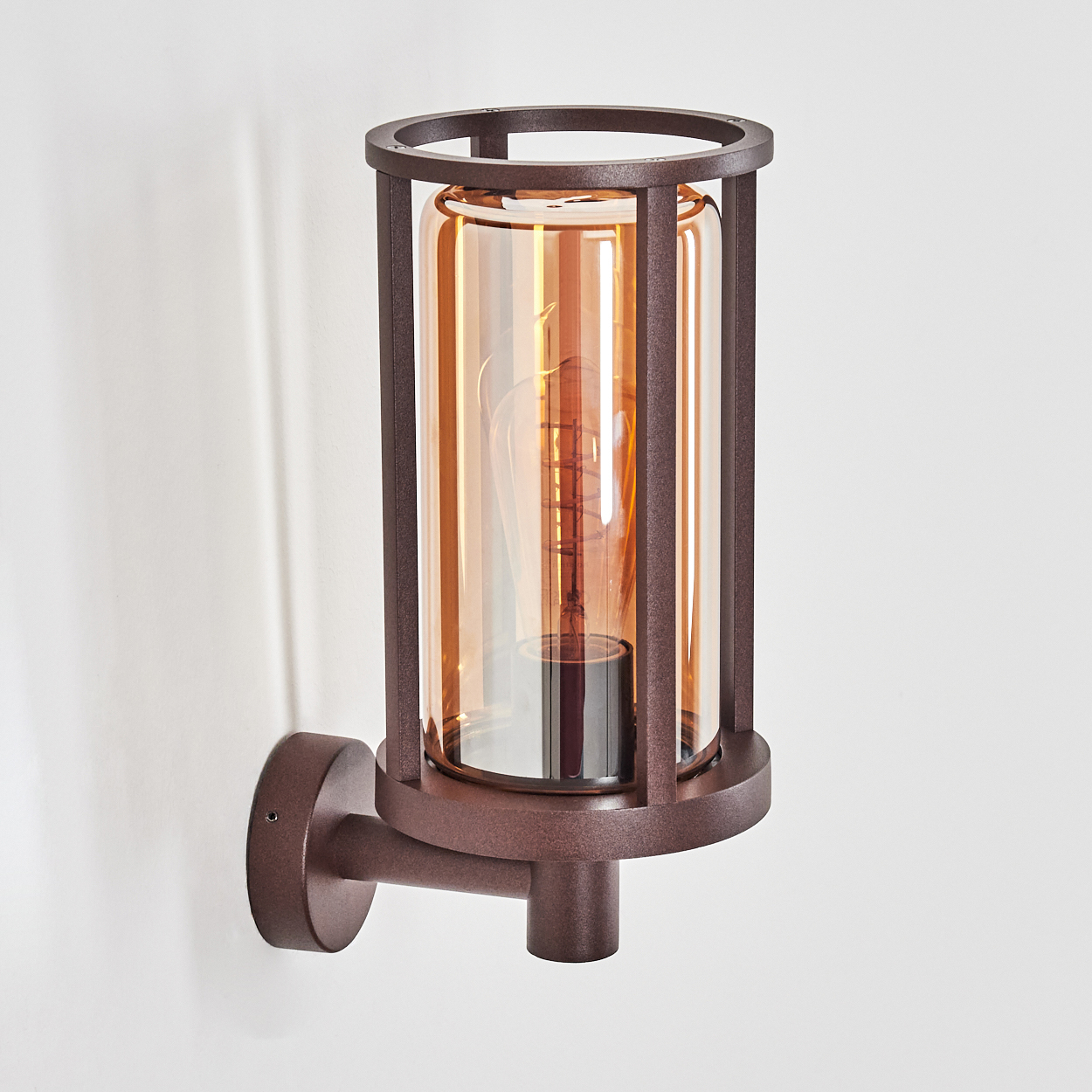 Eine Wandleuchte mit braunem Metallrahmen und bernsteinfarbenem Glasschirm auf weißem Hintergrund.