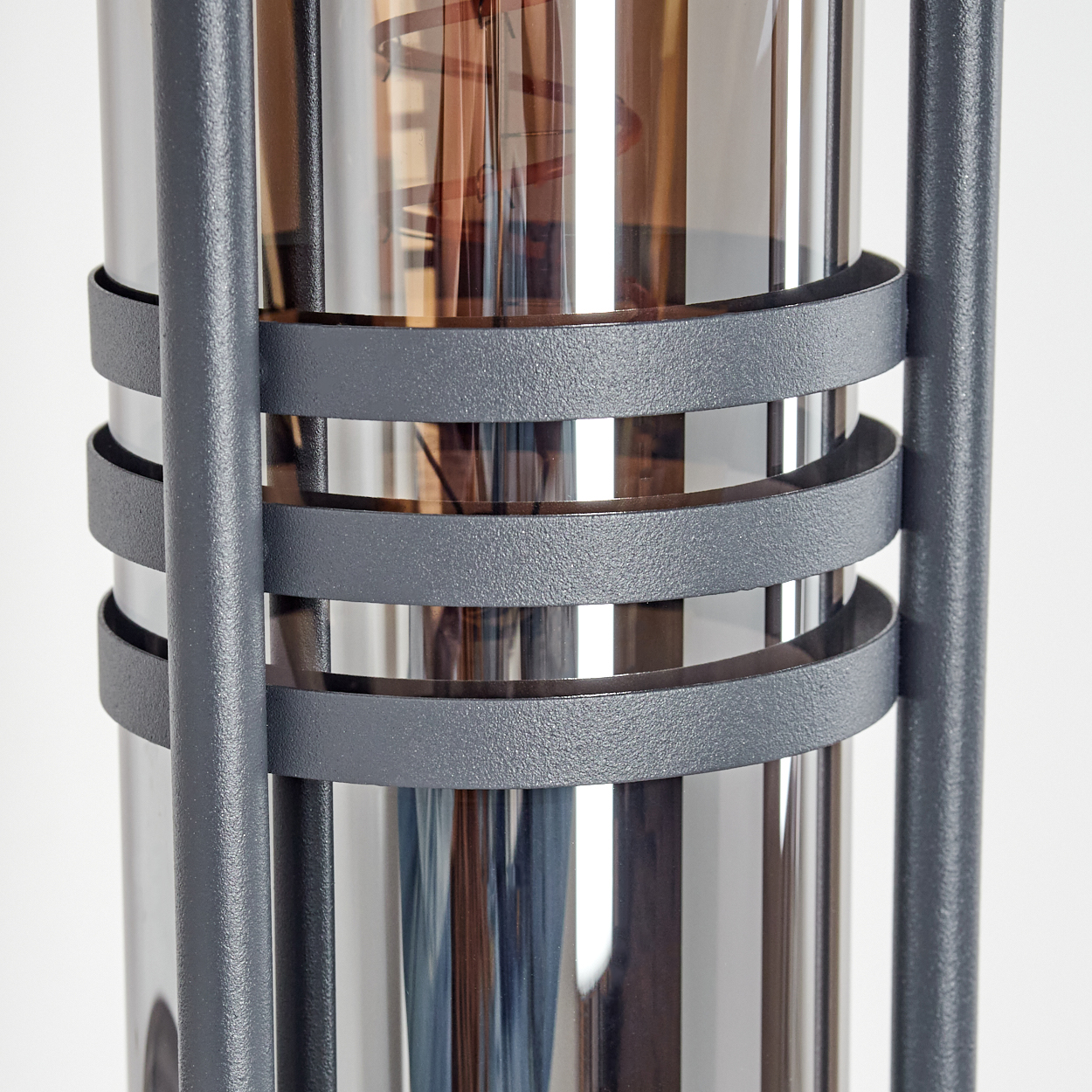 Nahaufnahme einer grauen Außenlampe, die die Metallbänder um einen silberfarbenen Zylinder zeigt.