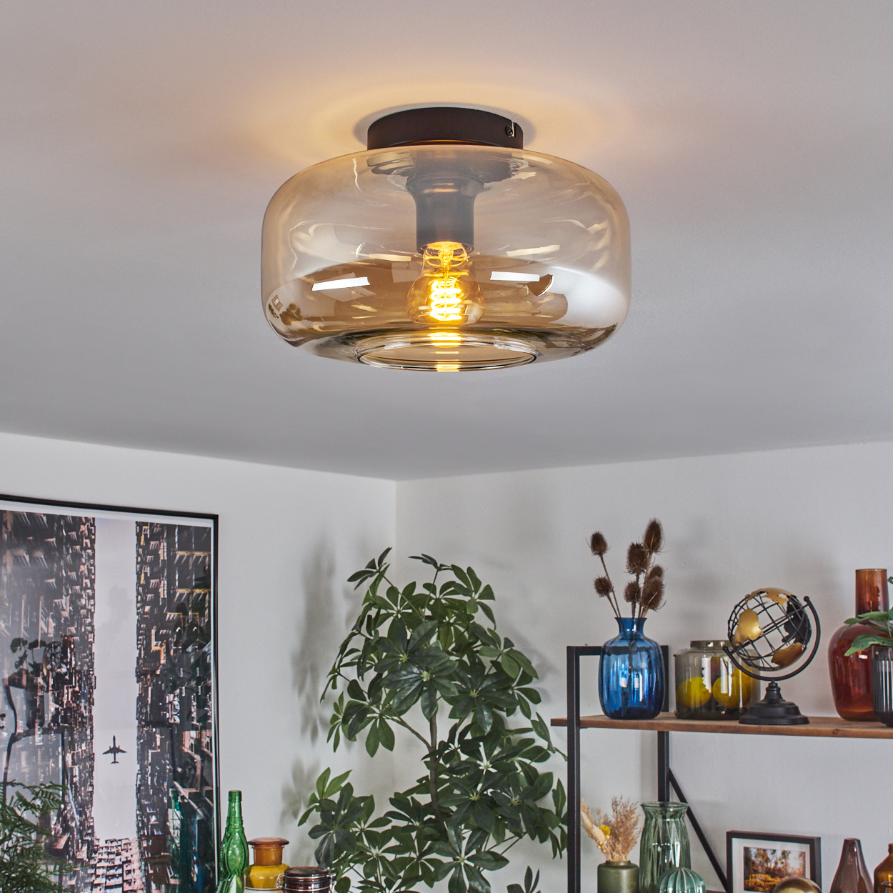 Deckenleuchte mit Glasschirm und Glühbirne, mit Inneneinrichtung im Hintergrund.