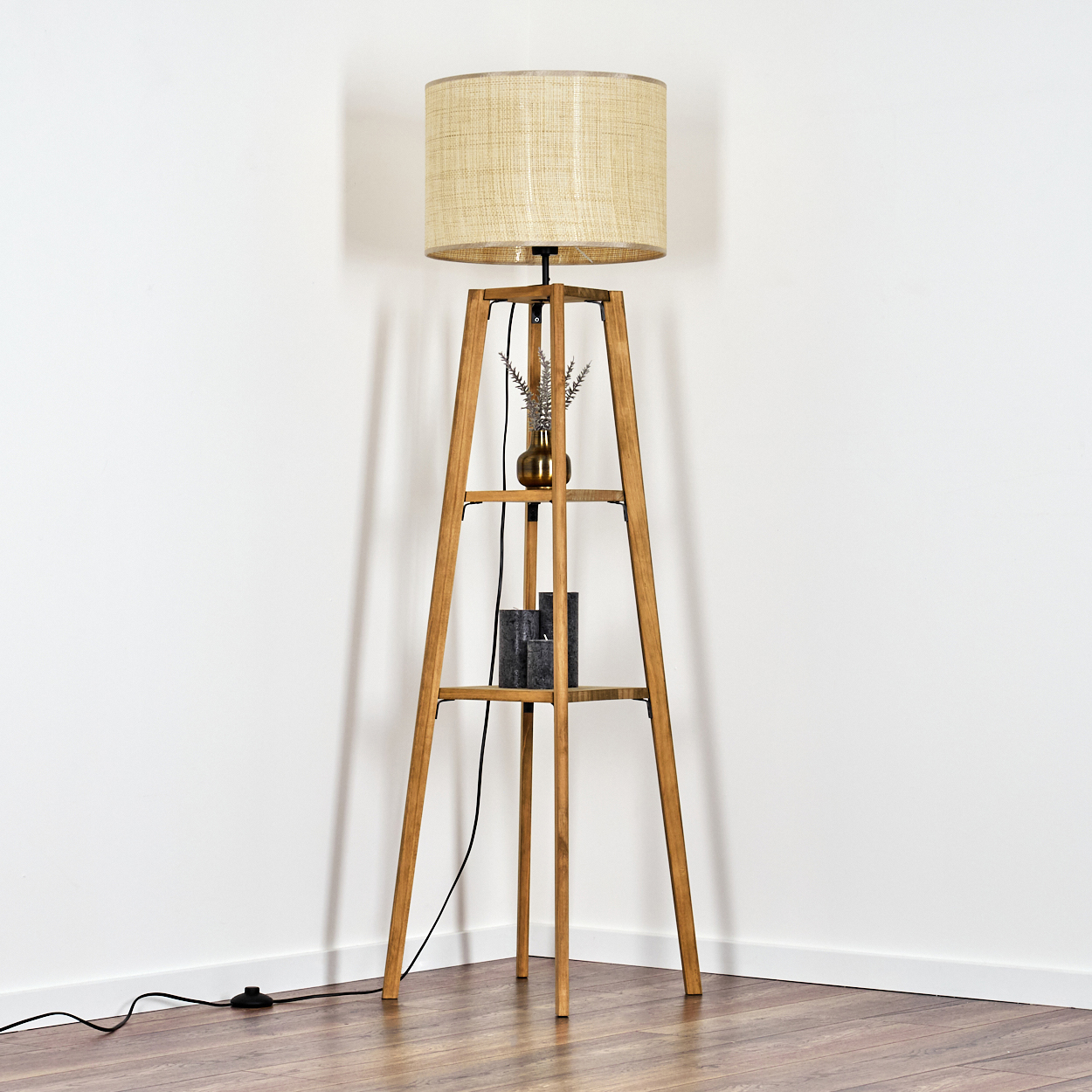 Stehlampe aus Holz mit beigem Schirm, Vase mit Blumen und einem schwarzen Deko-Artikel.