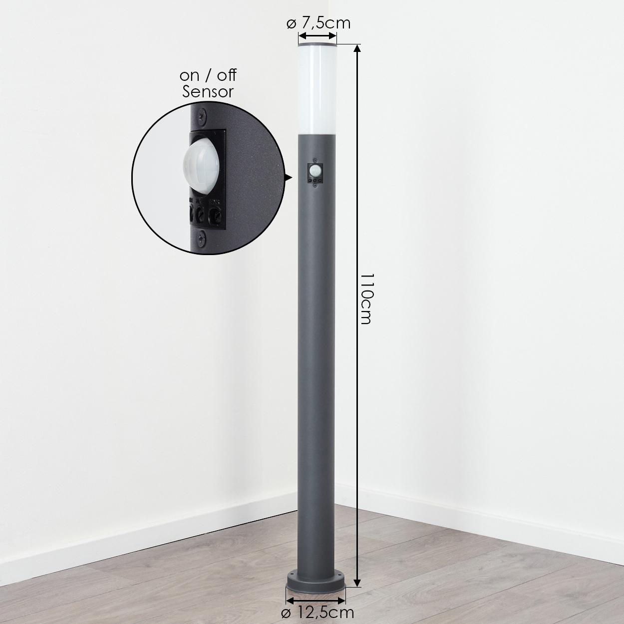 Eine hohe, graue Außenlampe mit Ein-/Aus-Sensor, vor einer weißen Wand.