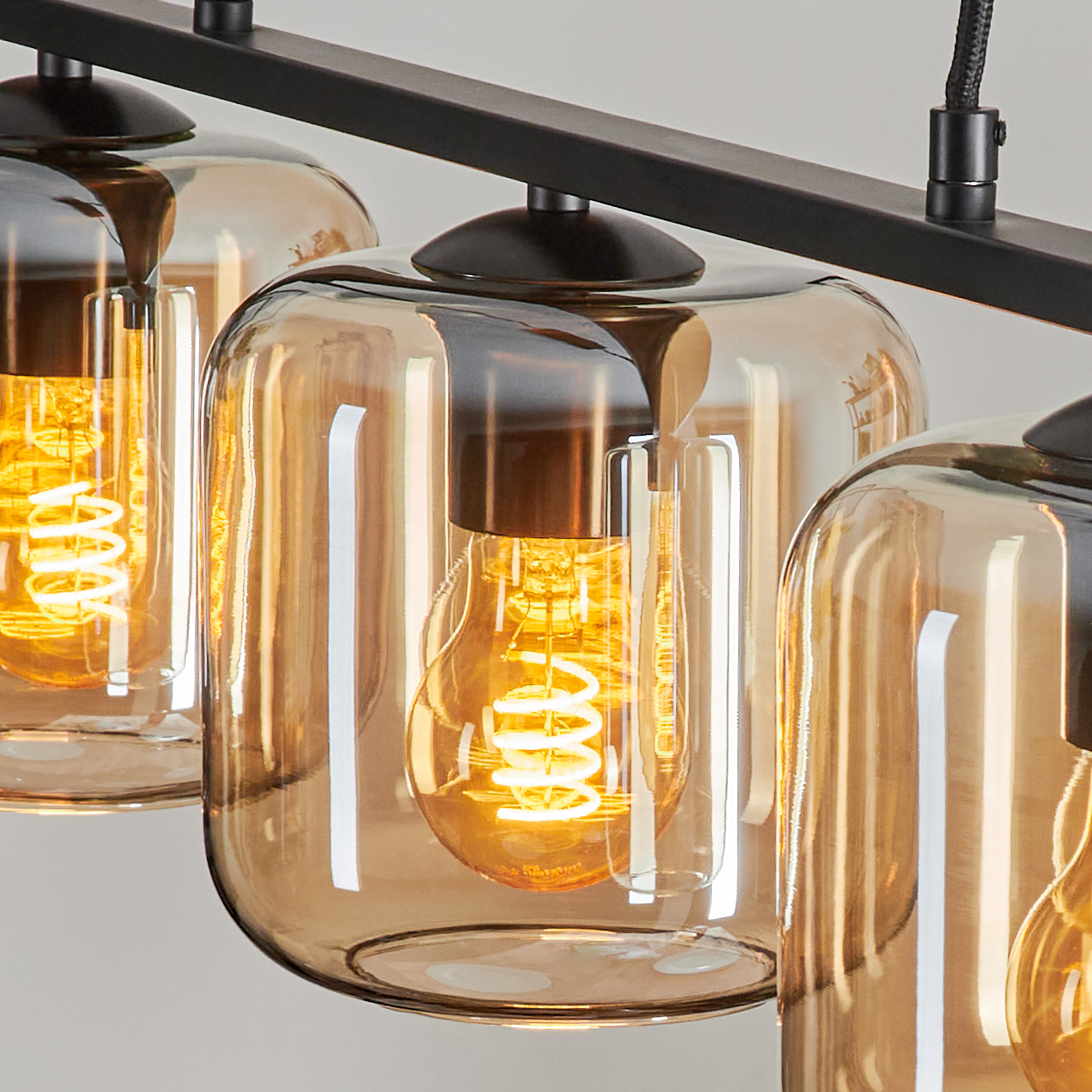 Nahaufnahme von drei Lampen mit bernsteinfarbenen Glasschirmen und sichtbaren Glühbirnen.