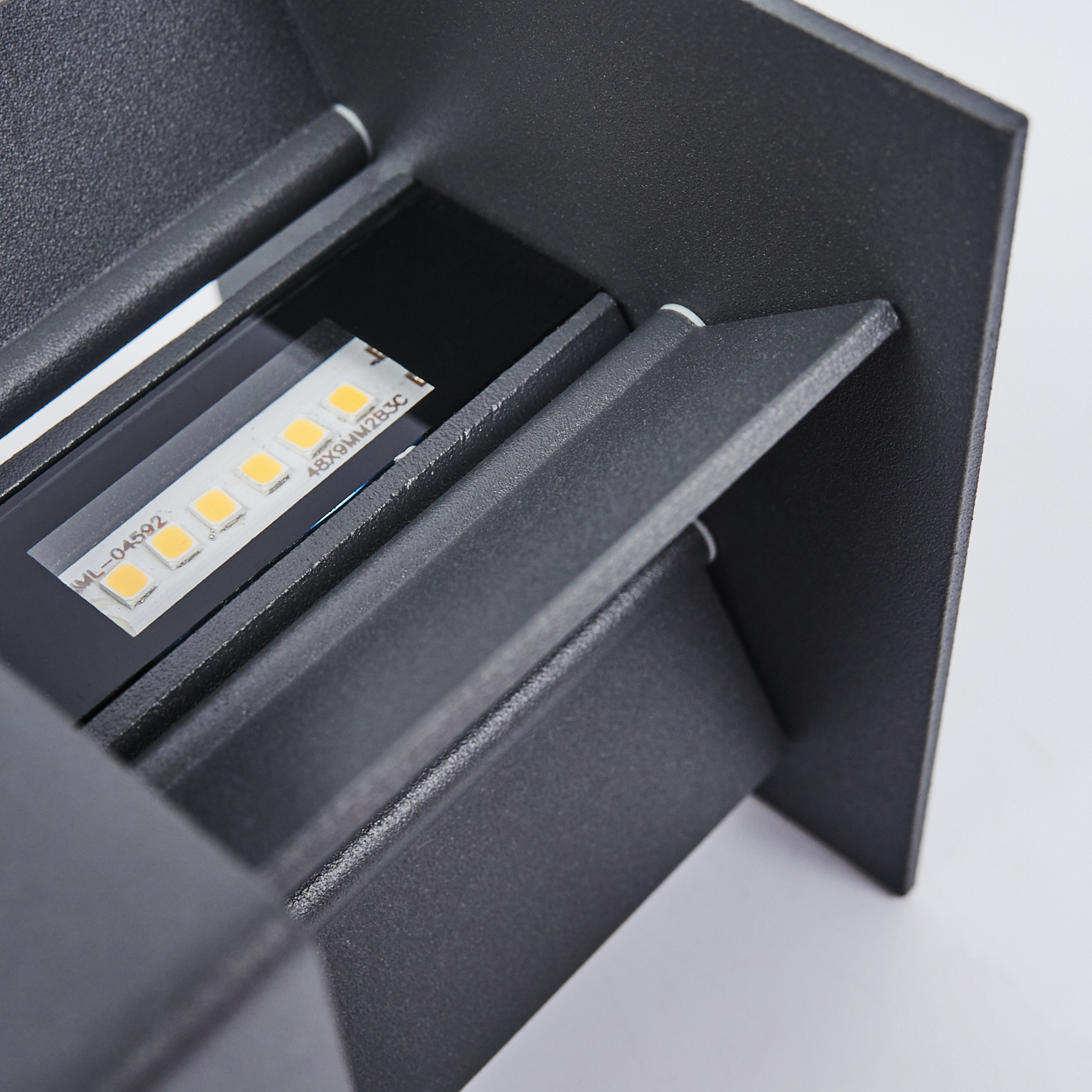 Nahaufnahme einer schwarzen Metallleuchte mit LED-Streifen. Weißer Hintergrund.