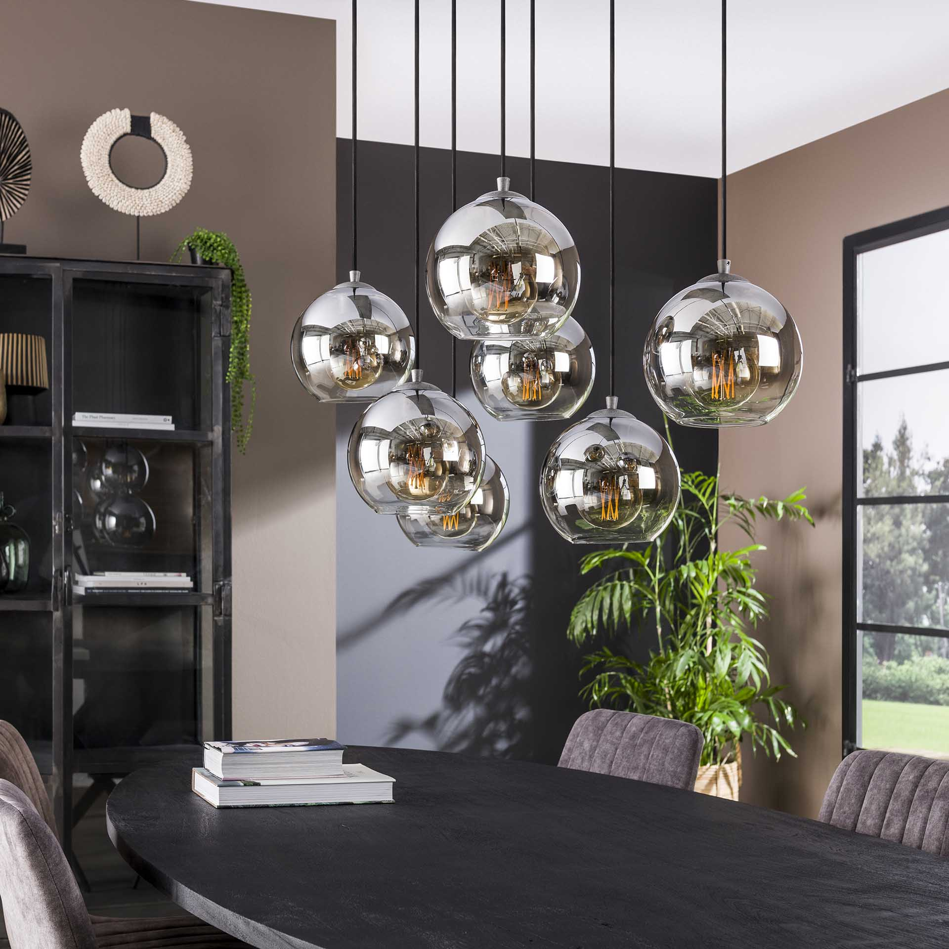 Esszimmer mit Hängelampen, dunklem Tisch, Dekoration und Pflanzen. Braune Wände.