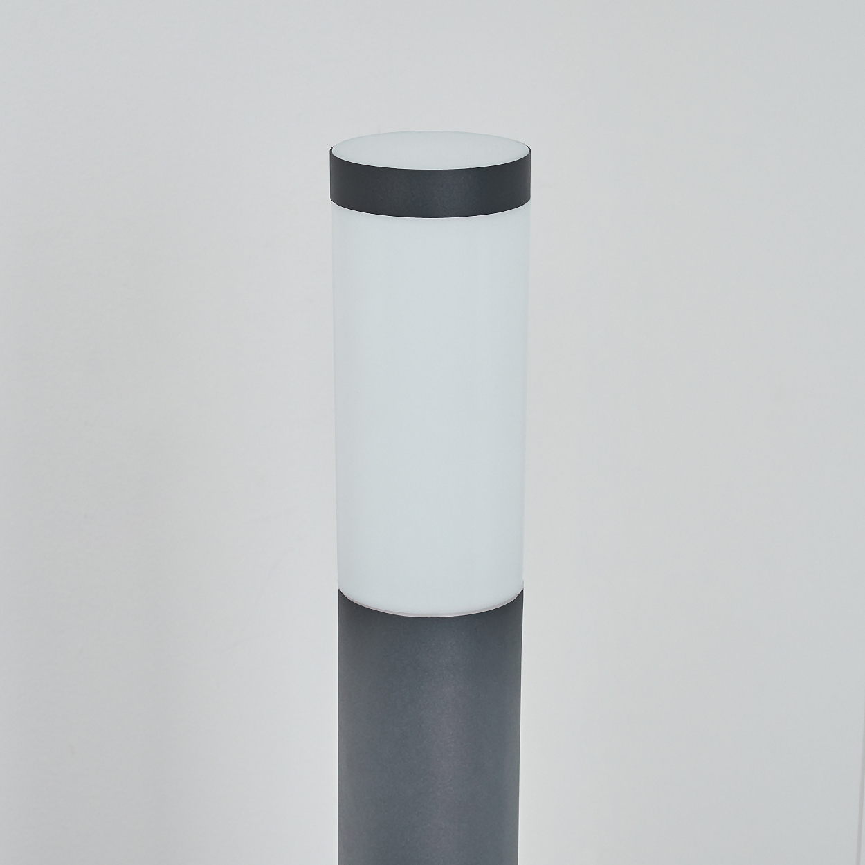 Eine zylindrische Lampe, grauer Sockel mit weißem Oberteil. Das Oberteil ist auch zylindrisch.