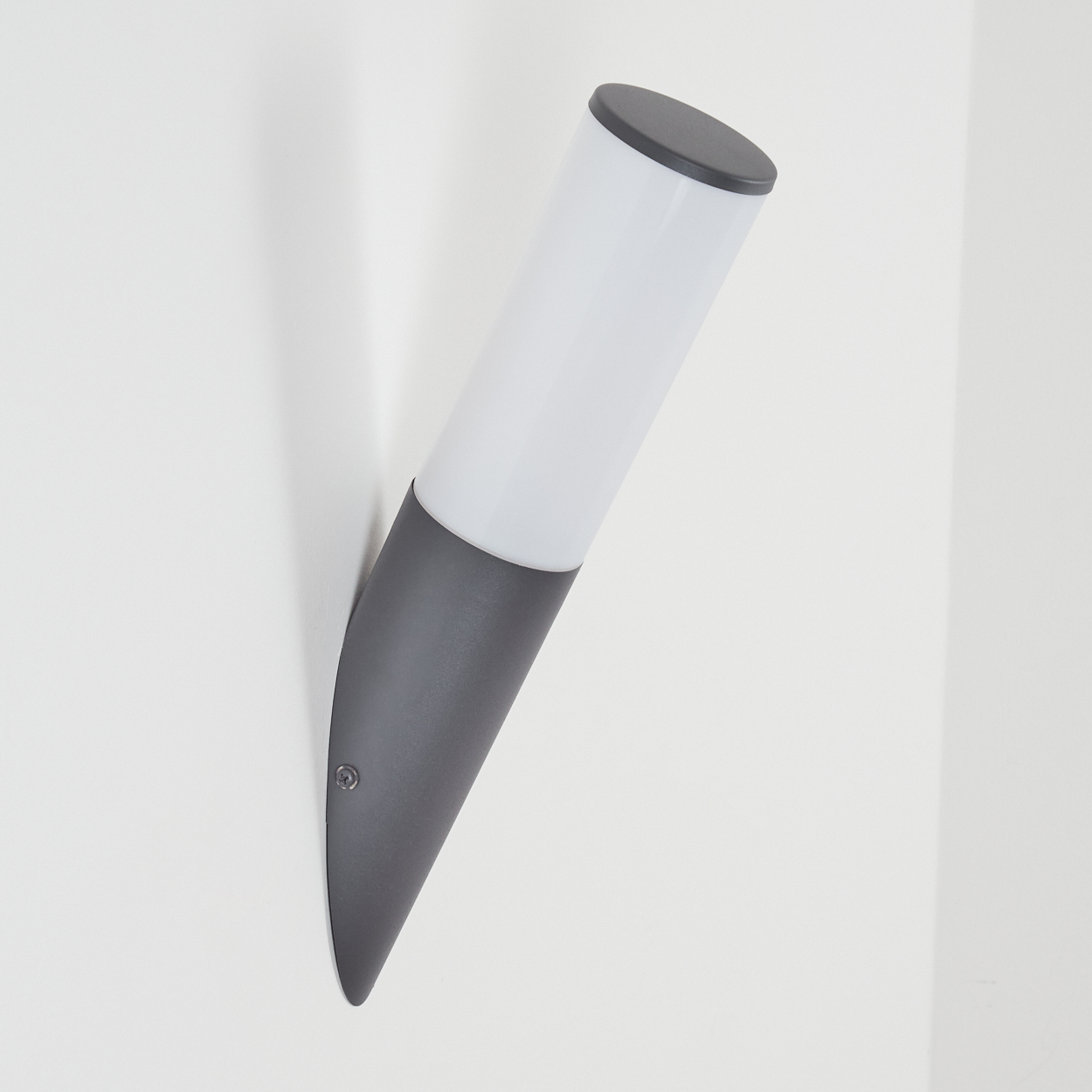 Graue und weiße Wandleuchte, an einer weißen Wand angewinkelt. Zylindrisches Design.
